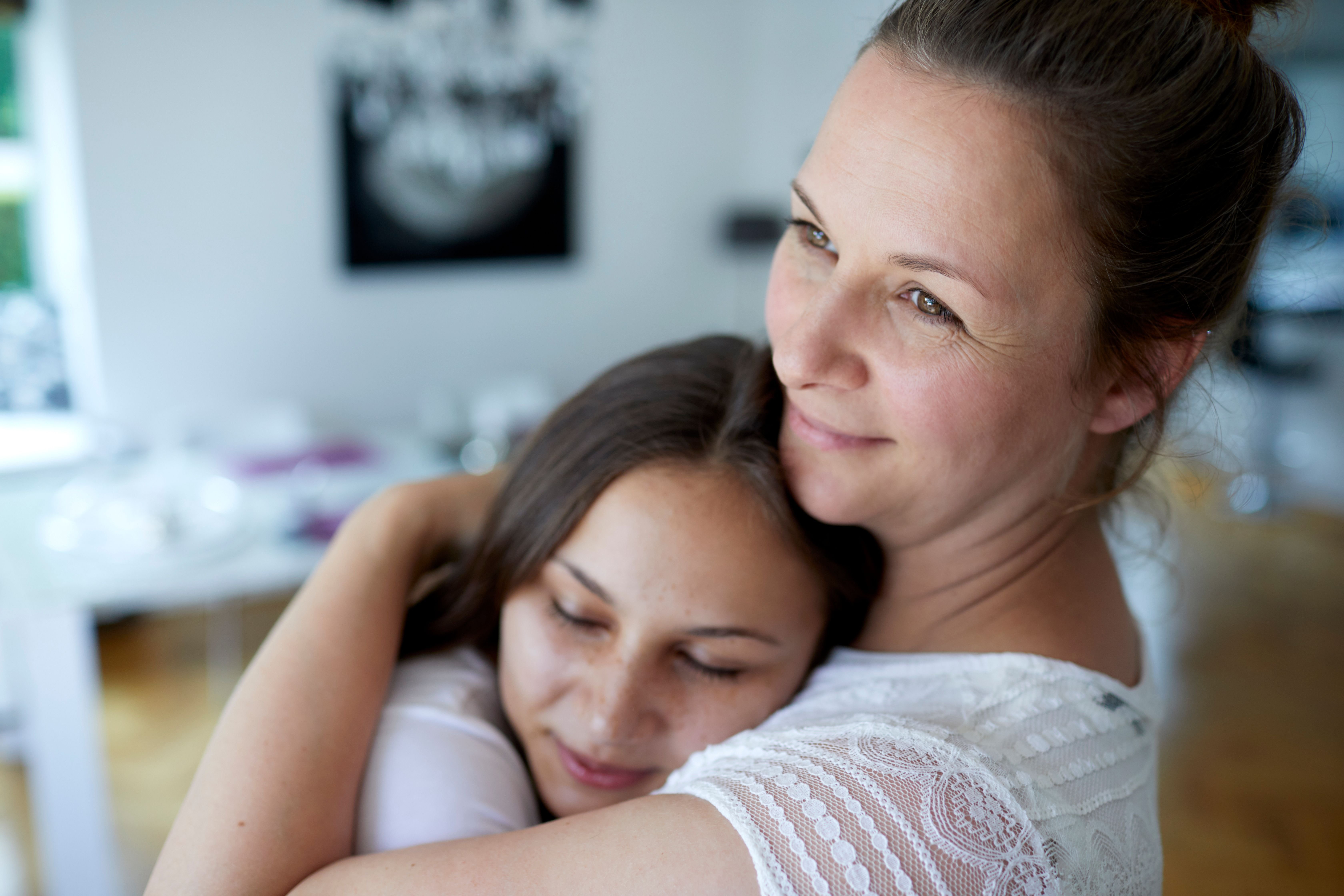 A mother and her teen daughter hugging at home. | Source: Getty Images