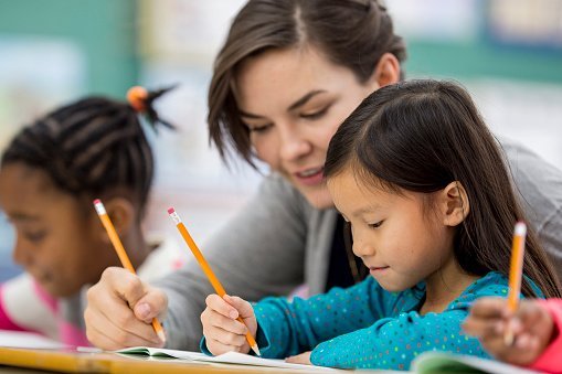 A teacher conversing with a student work in the classroom | Photo: Getty Images