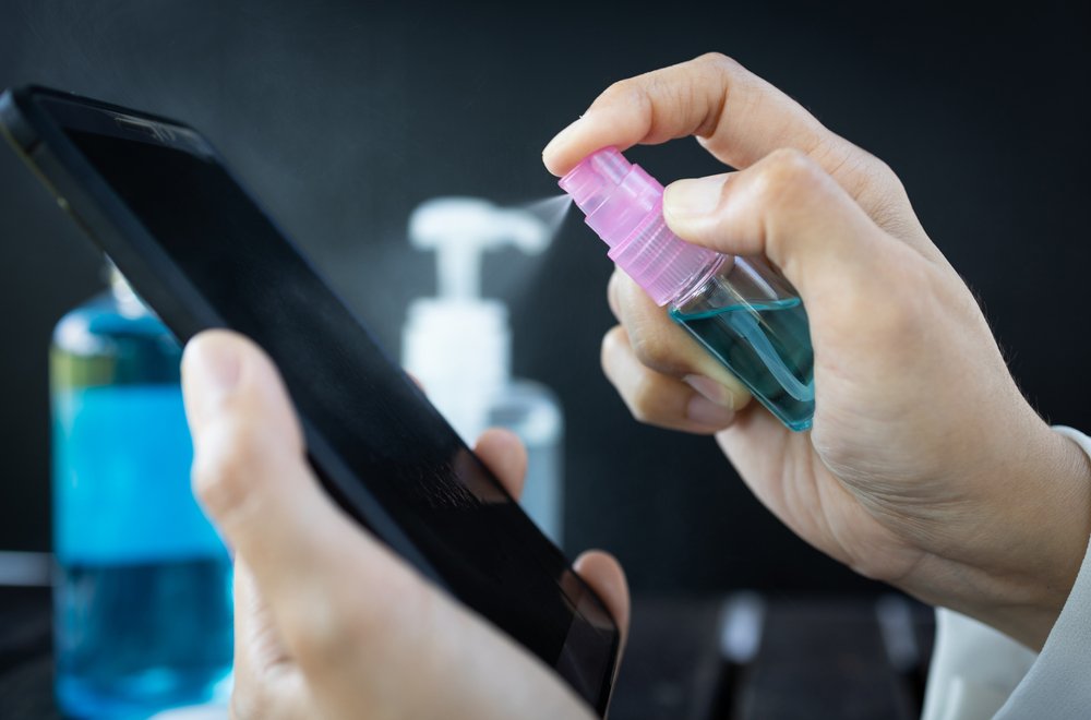 Mujer rocía desinfectante en spray en el teléfono móvil para prevenir la infección del virus Covid-19. | Foto: Shutterstock Mujer rocía desinfectante en spray en el teléfono móvil para prevenir la infección del virus Covid-19. | Foto: Shutterstock