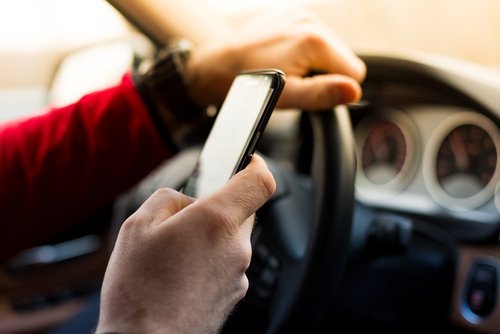 An adult texting and driving. | Source: Shutterstock.