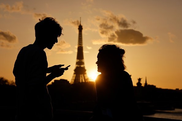Un couple, dont l'un vérifie son smartphone, profite de la vue de la Tour Eiffel.|Photo : Getty Images