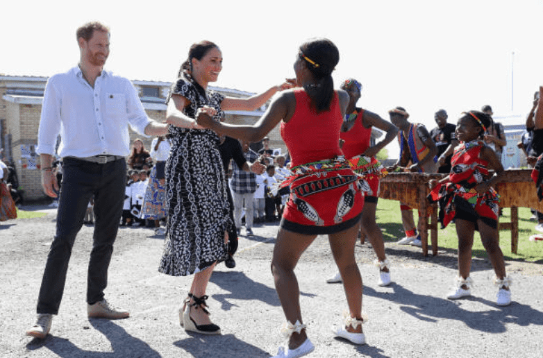 During their royal tour of Africa, Meghan Markle and Prince Harry dance with locals during a visit at the Justice Desk initiative in Nyanga township, on September 23, 2019, Cape Town, South Africa | Source: Getty Images