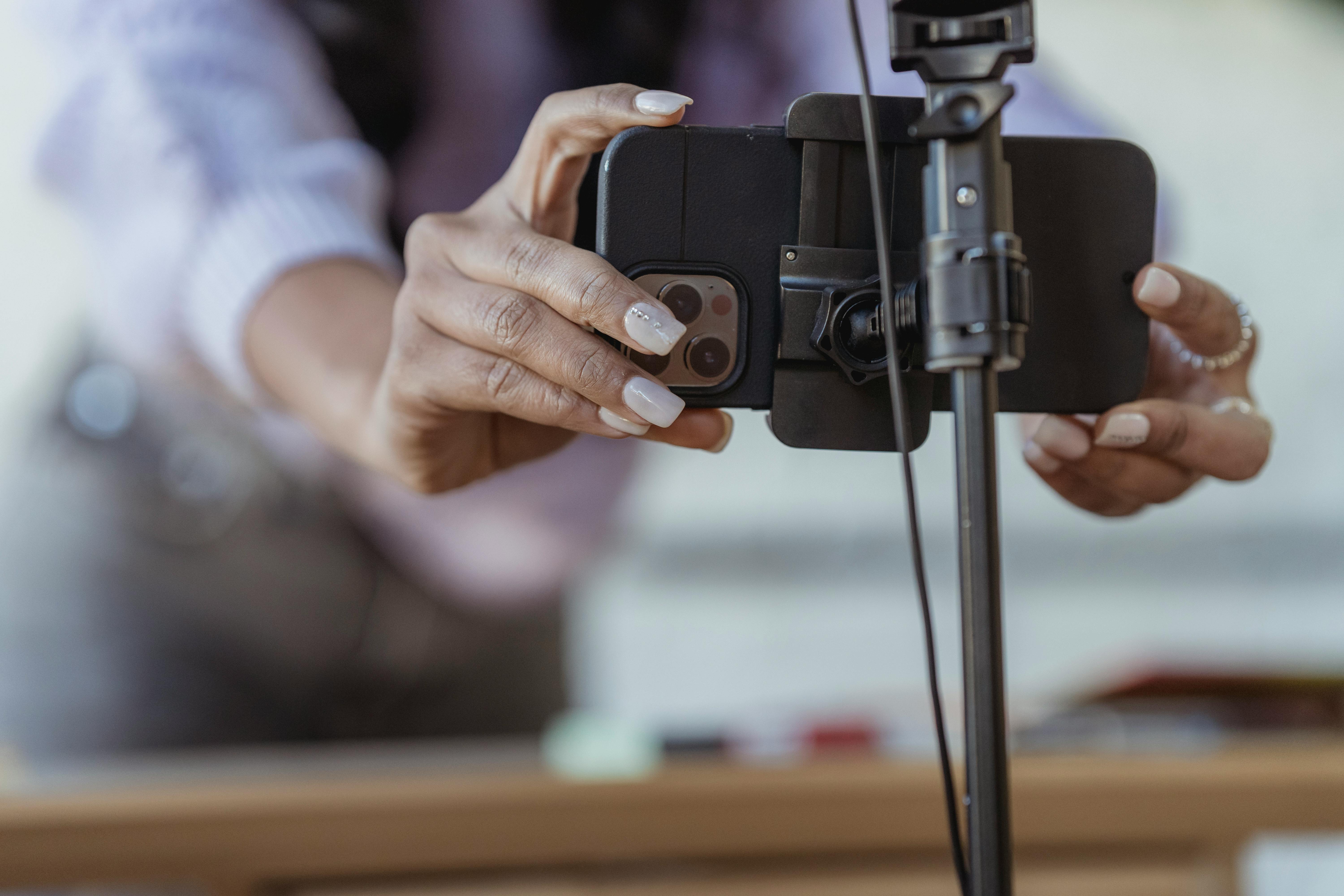 A woman fixing her phone on a tripod | Source: Pexels