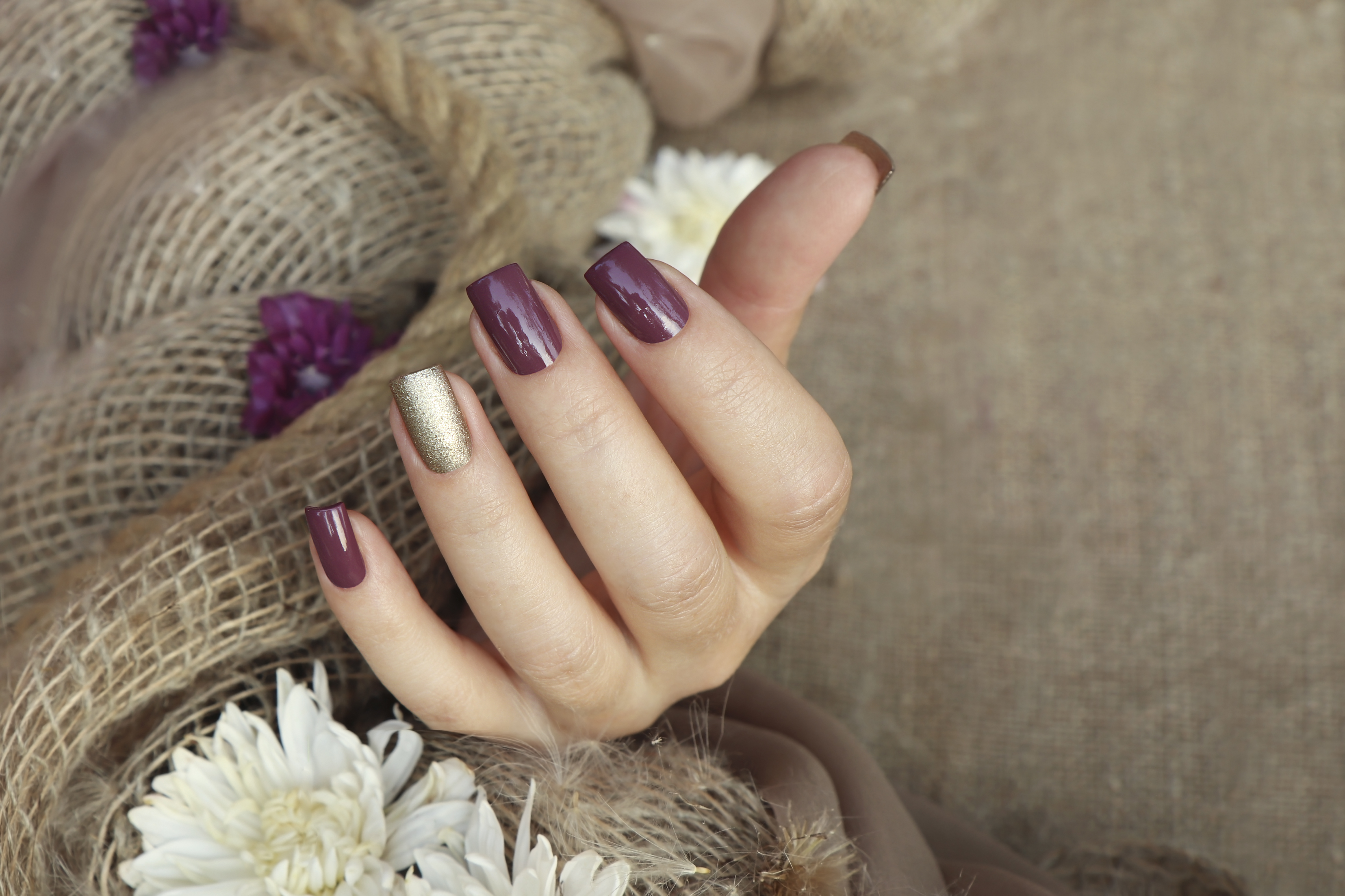 A female hand adorned with plum and golden nail hues | Source: Getty Images