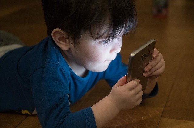 Niño viendo un teléfono celular. │ Foto: Pixabay