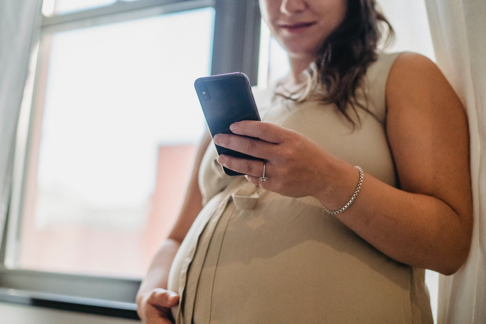Una mujer embarazada revisa su celular. | Foto: Pexels