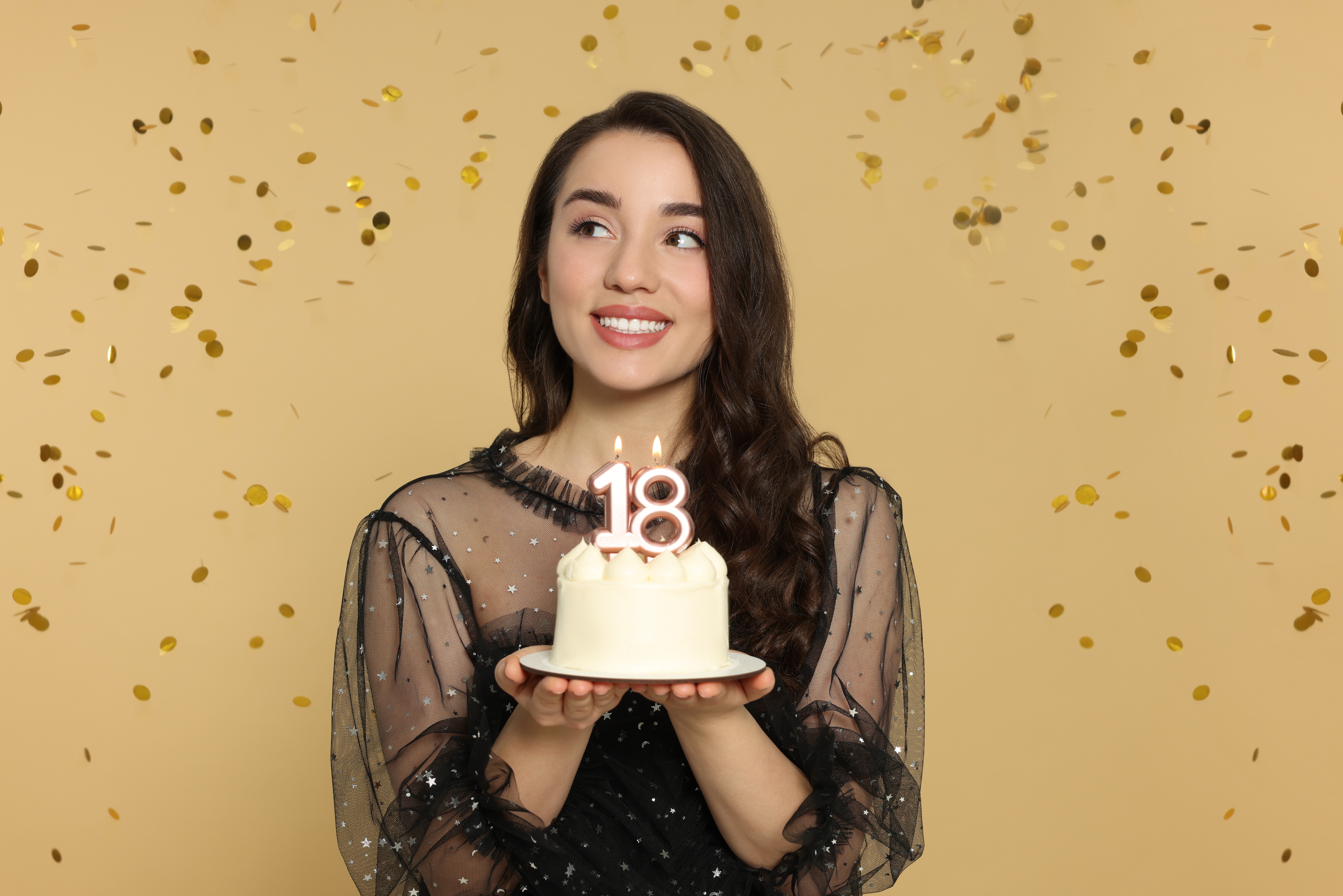A young woman holding her 18th birthday cake | Source: Shutterstock