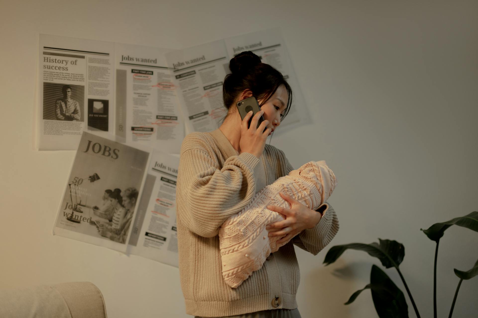 A woman talking on the phone while holding her baby | Source: Pexels