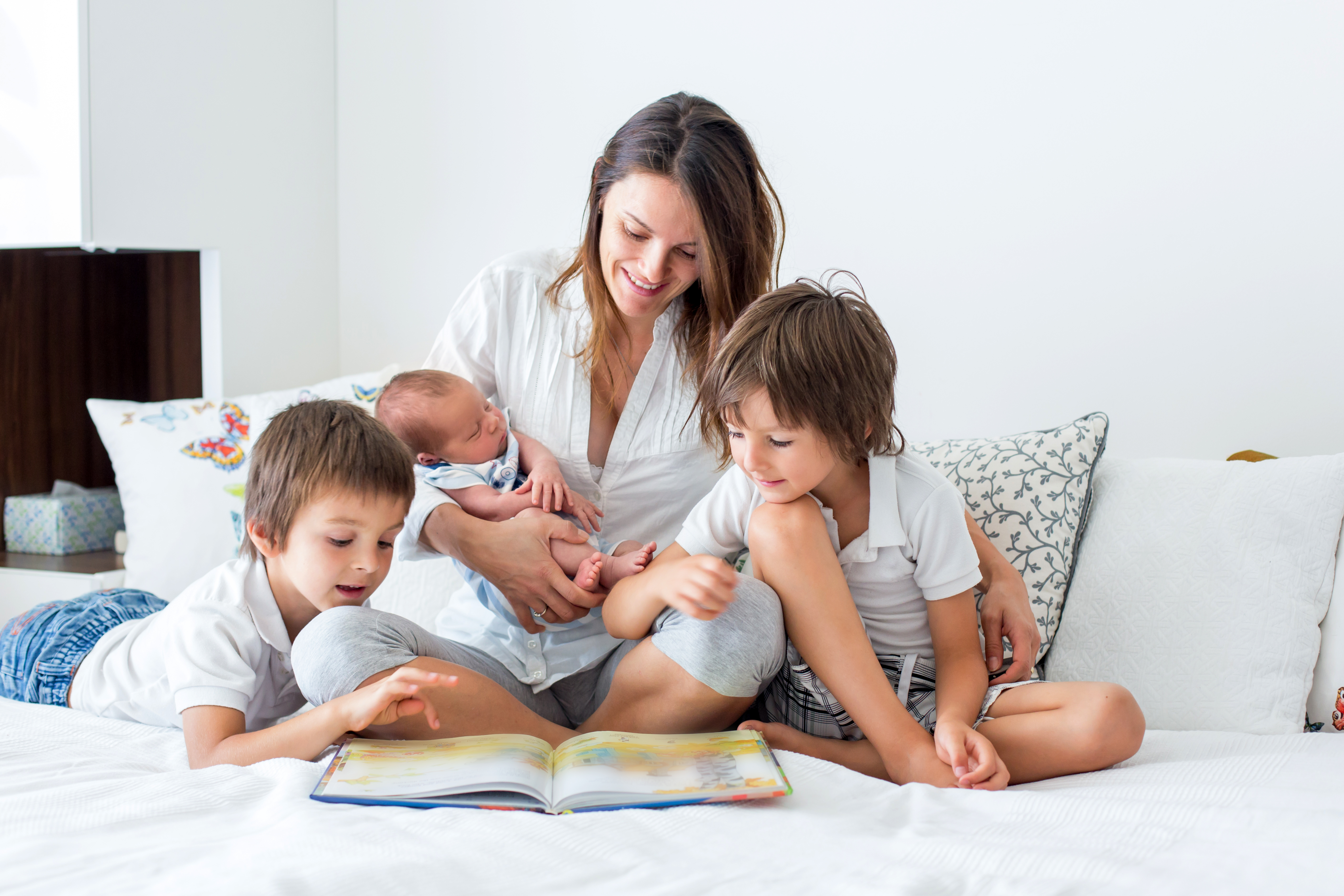 A young mother reading a book to her three kids | Source: Shutterstock