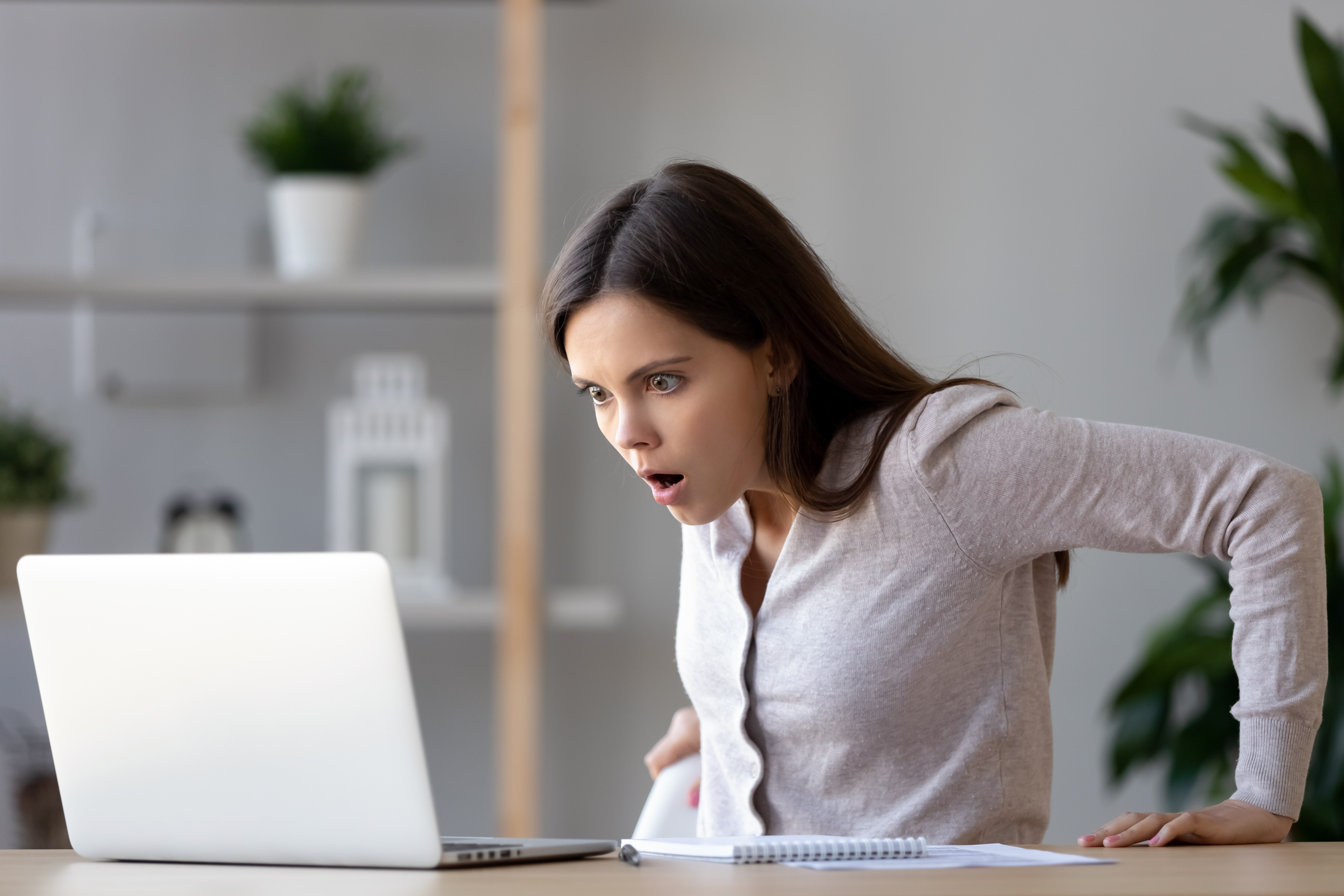A  young woman looking shocked at what she's seeing in a laptop | Source: Shutterstock