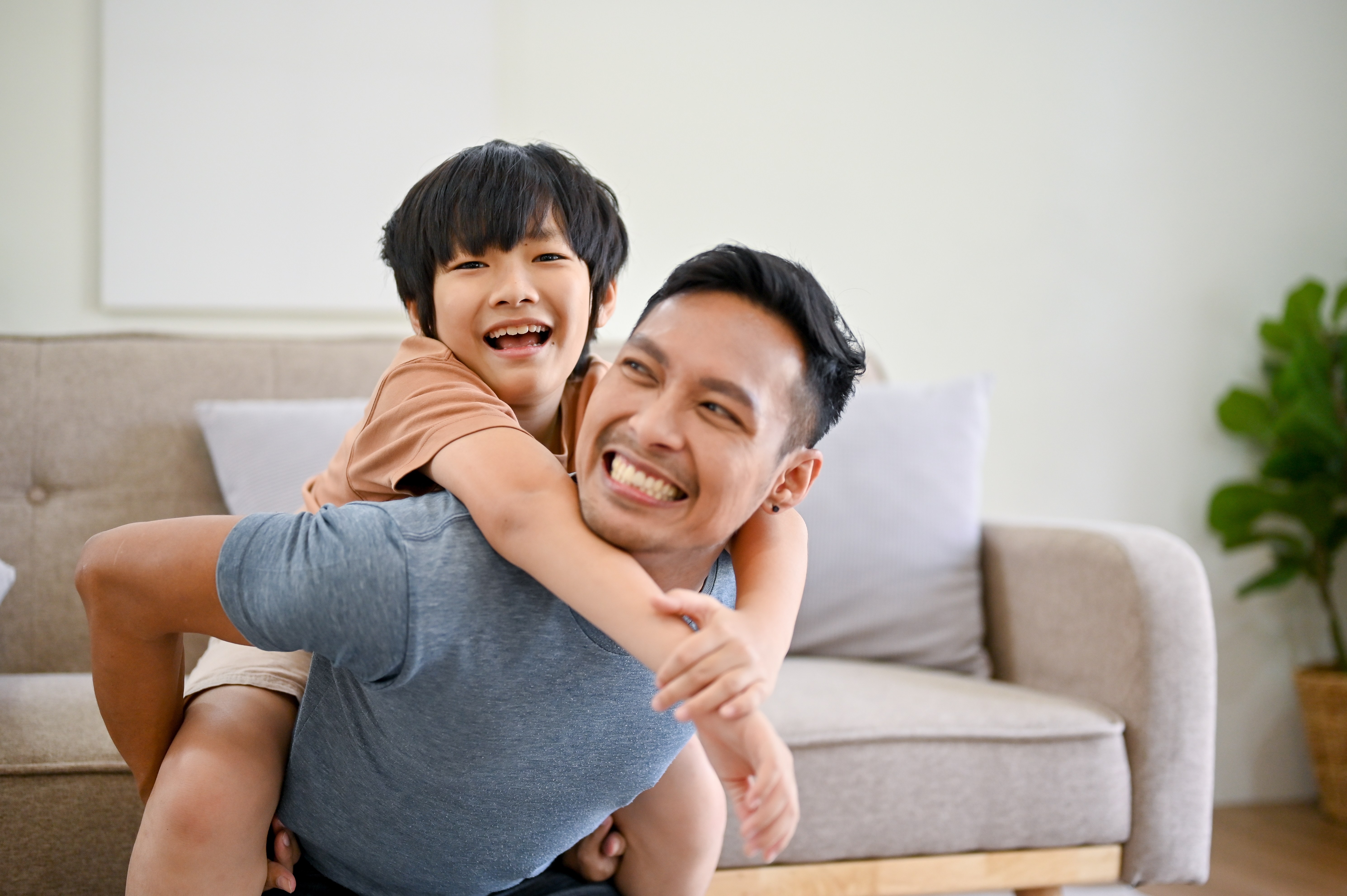 Asian son on his father's back, smiling | Source: Shutterstock