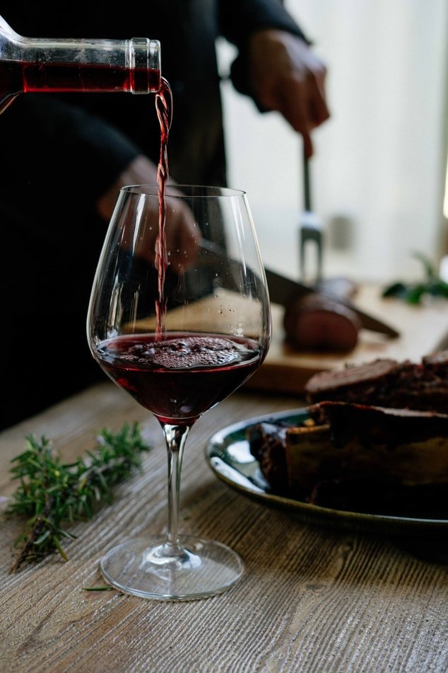 Pouring a glass of red wine | Source: Unsplash