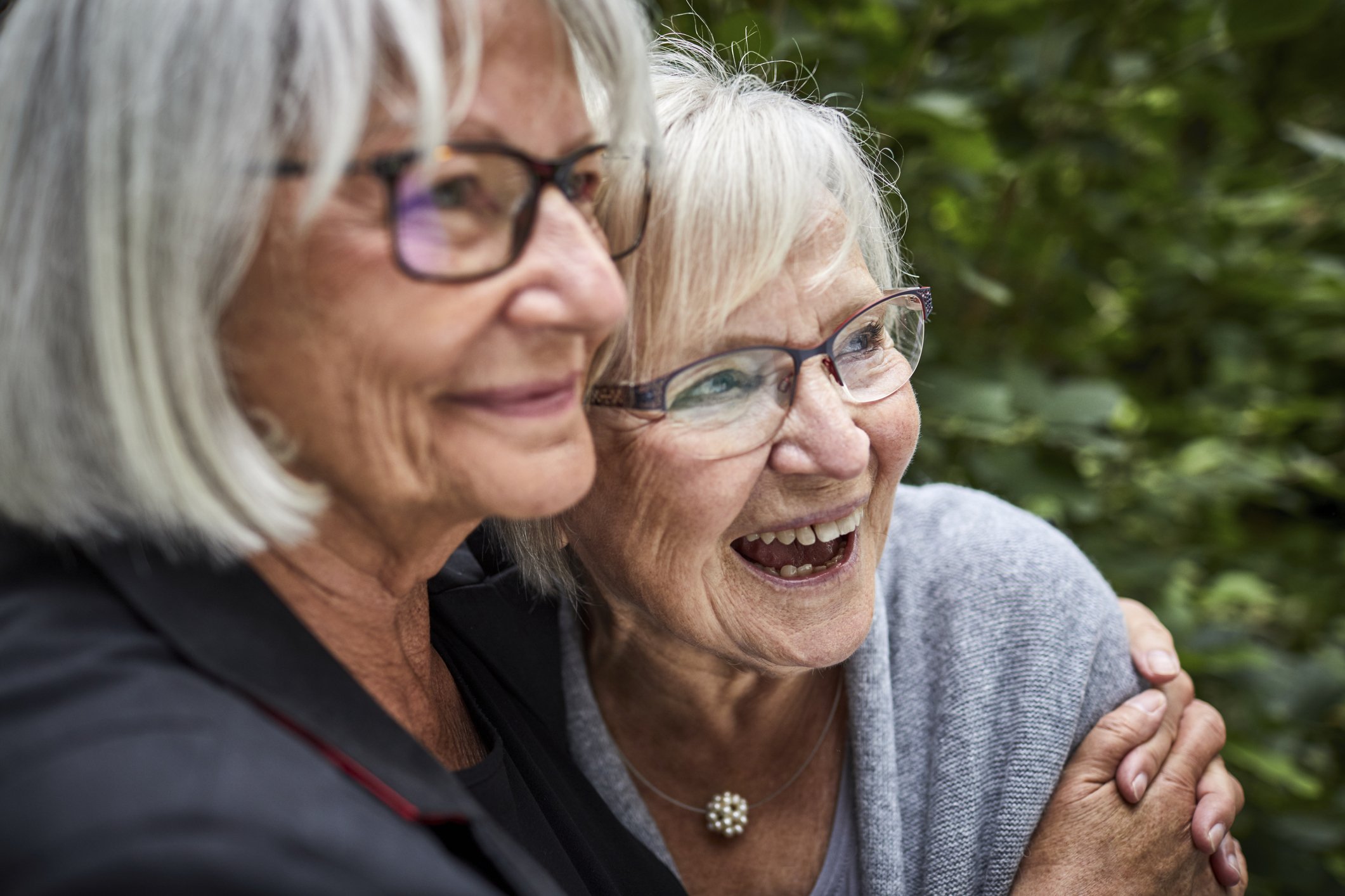 An image showing two senior women hugging each other in a garden. | Photo: Getty Images