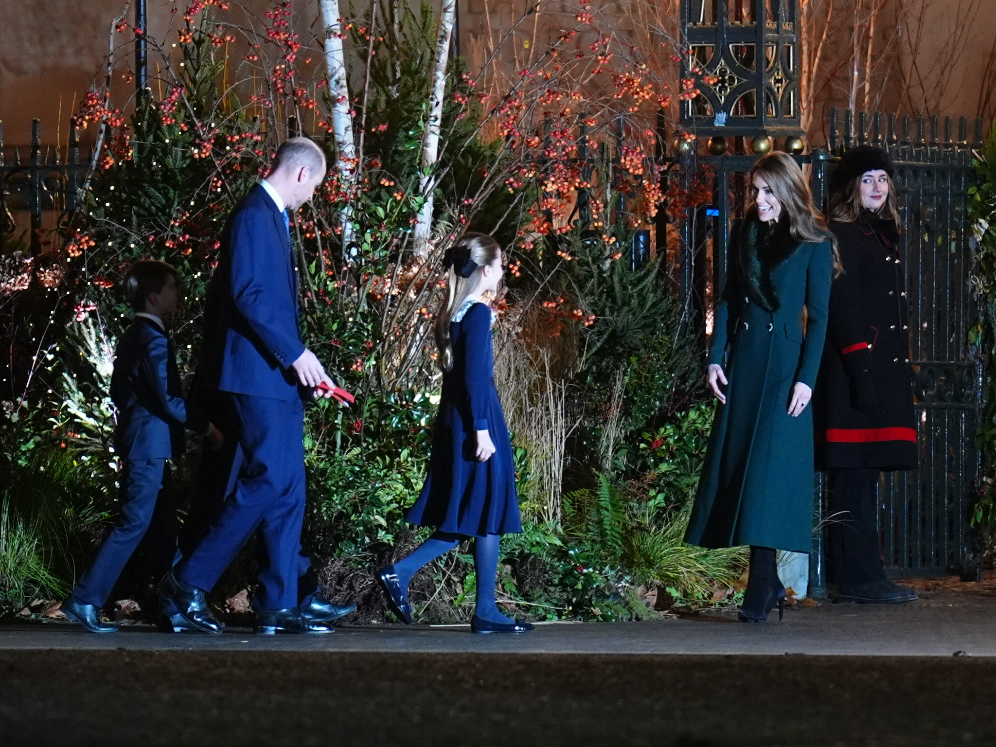 With Catherine, Princess of Wales, waiting near the gate in her emerald Catherine Walker coat, the rest of the Wales family — led by Princess Charlotte — makes their way toward her. The moment captured a warm, anticipatory energy, as the five gathered ahead of the festive carol service.