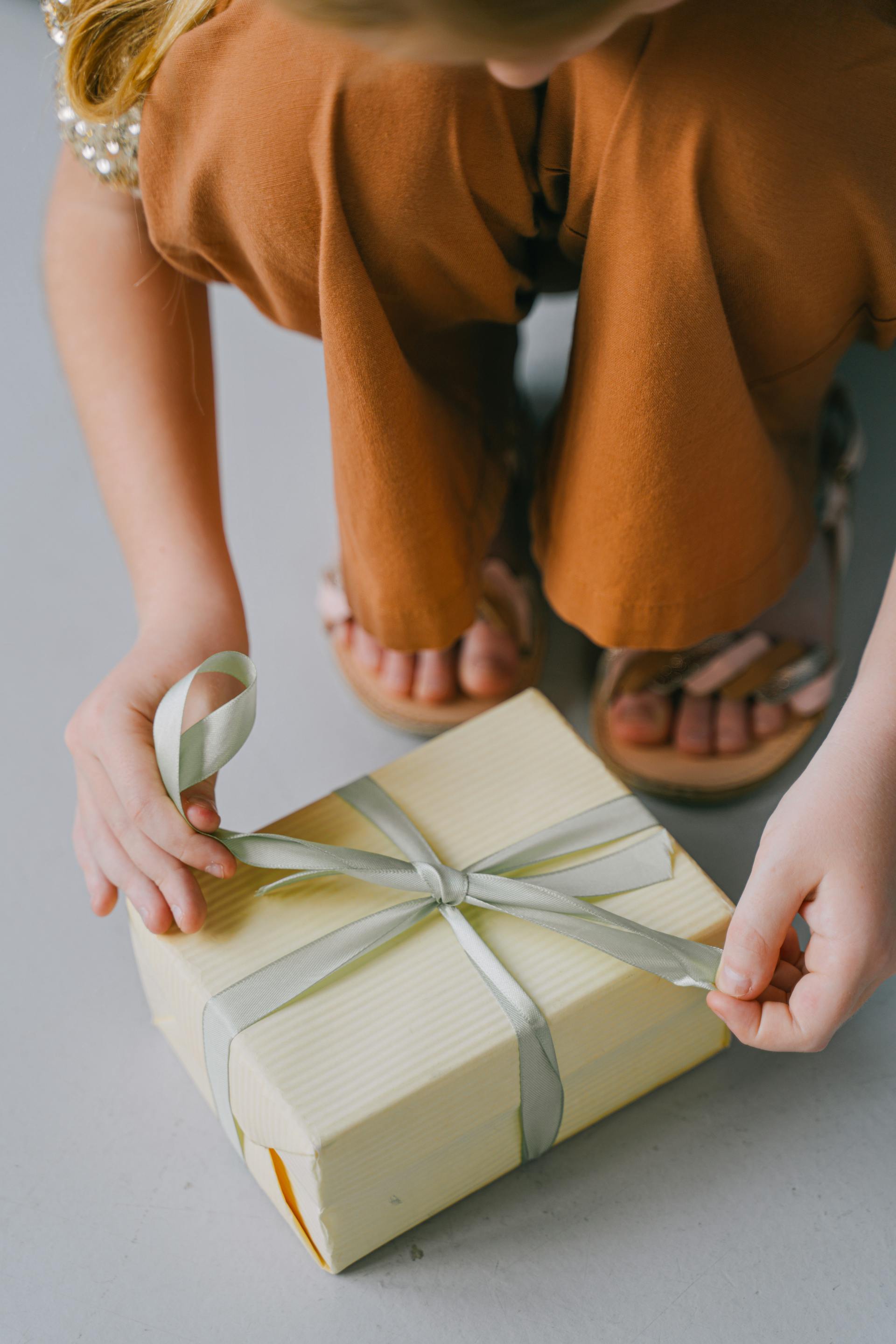 A woman tying the ribbon on a gift box | Source: Pexels