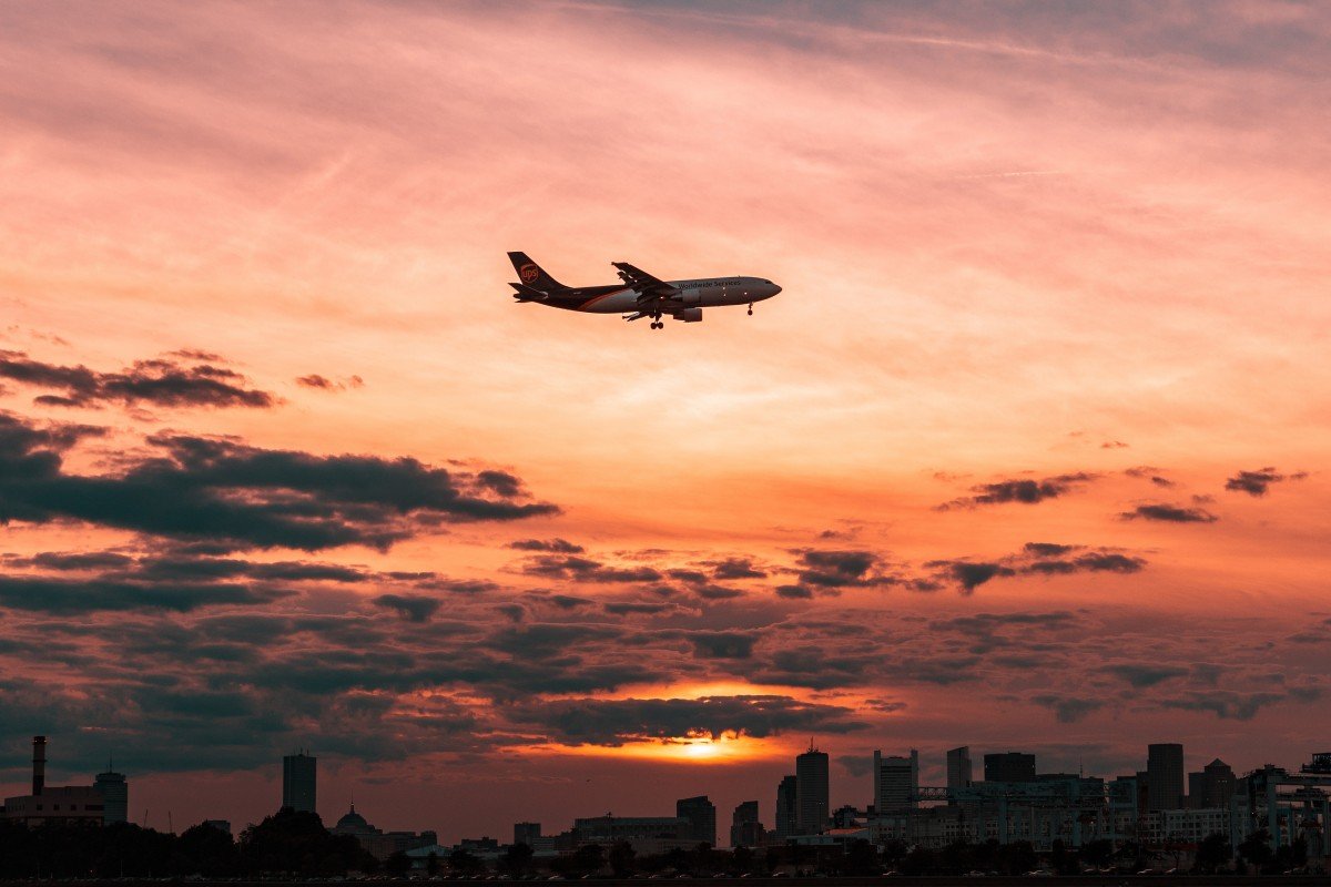 Avión volando sobre la ciudad durante el atardecer. | Foto: PxHere