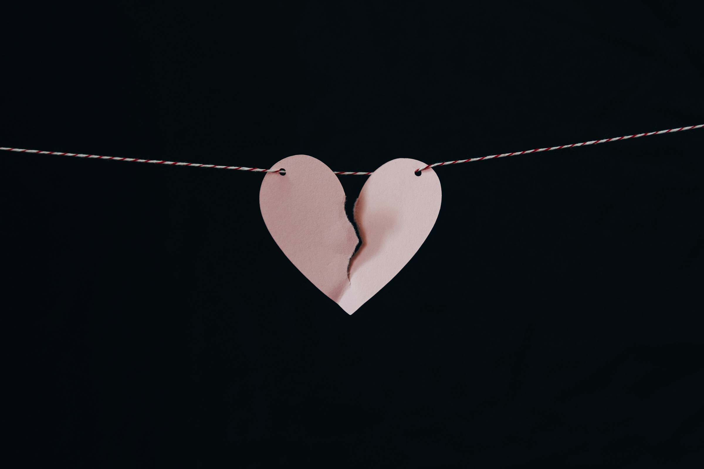 A broken paper heart hanging on a wire | Source: Unsplash