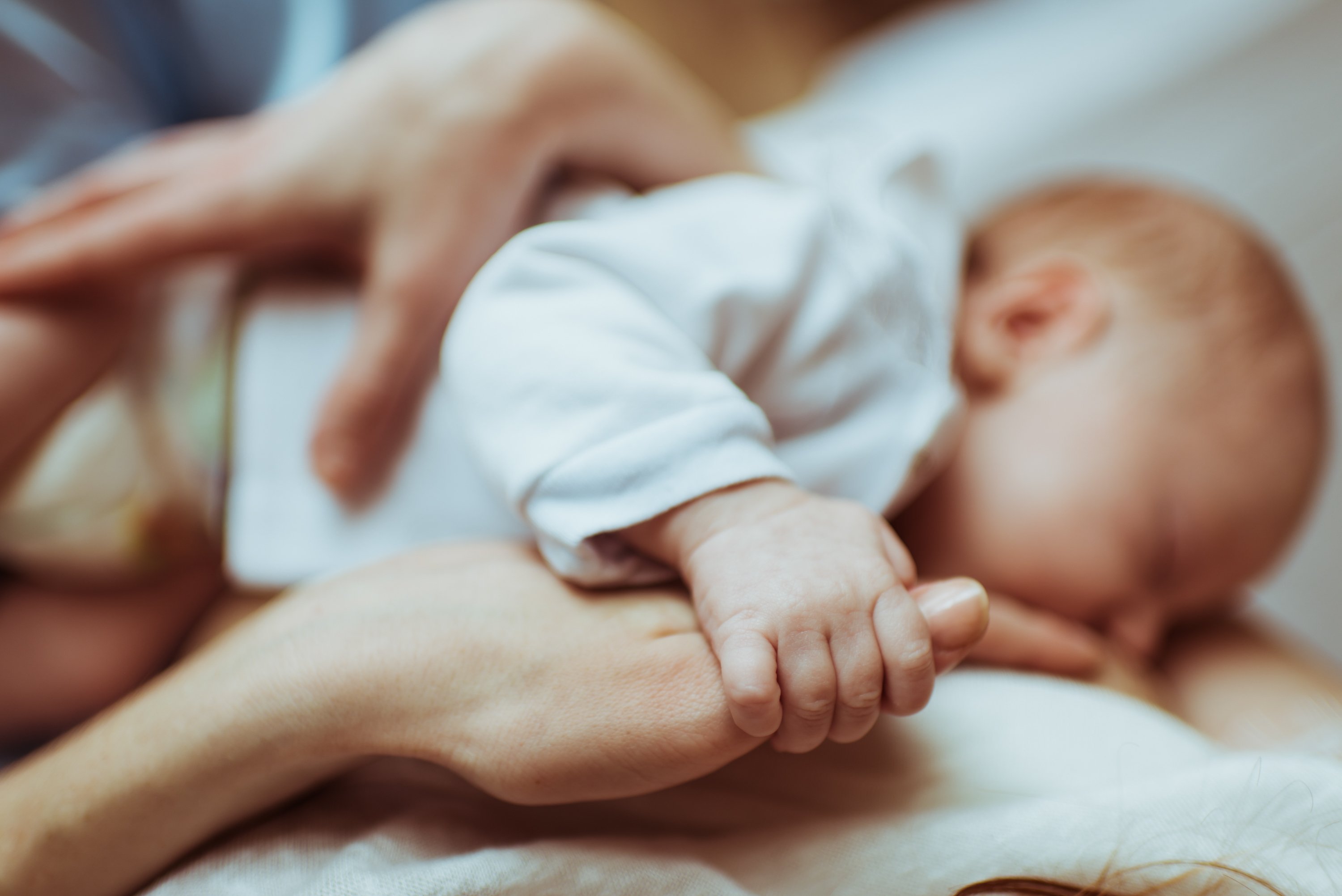 Bebé sostiene la mano de su mamá mientras duerme. | Foto: Shutterstock