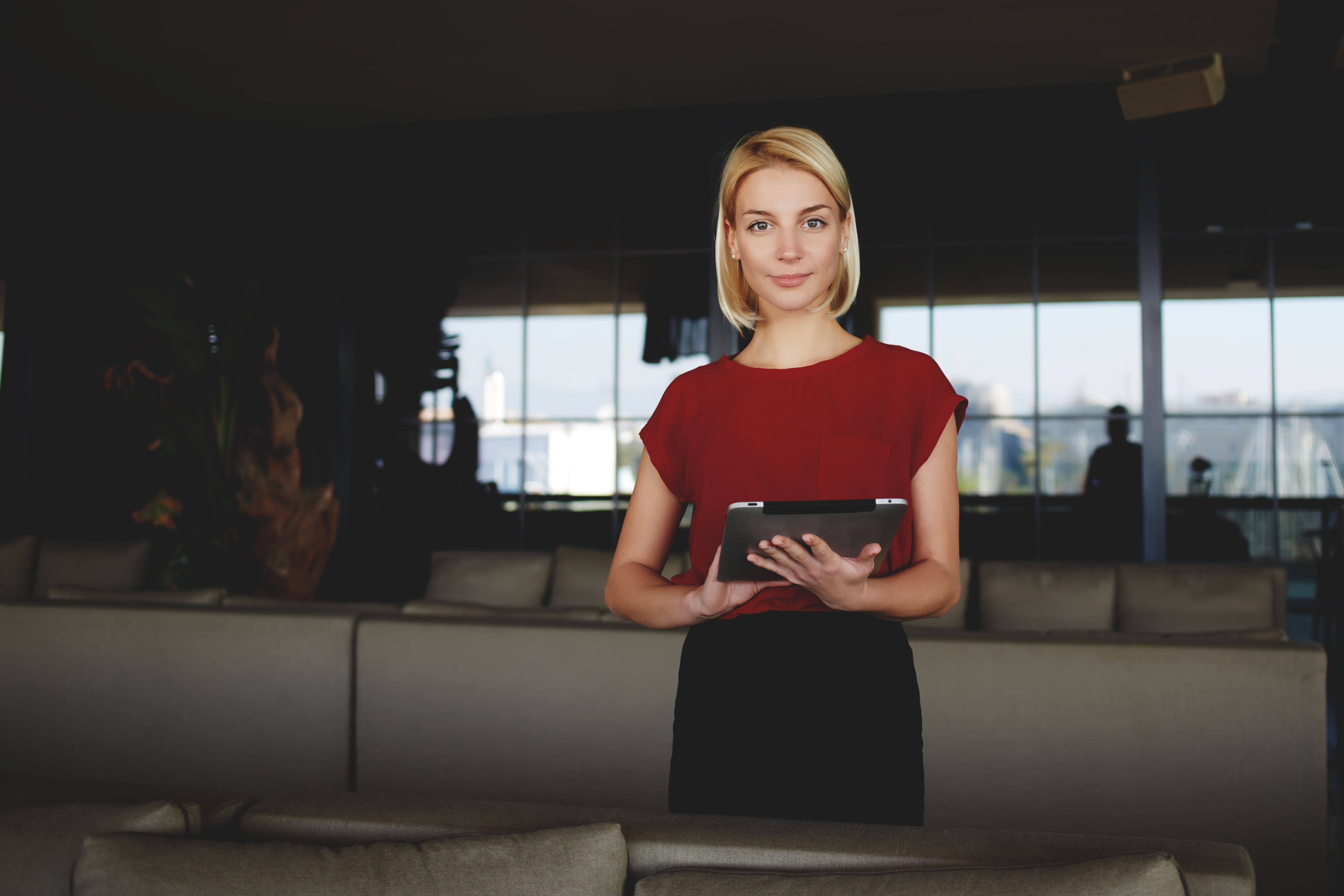 Young gorgeous businesswoman holding in hands digital tablet while standing in modern restaurant interior | Source: Shutterstock.com