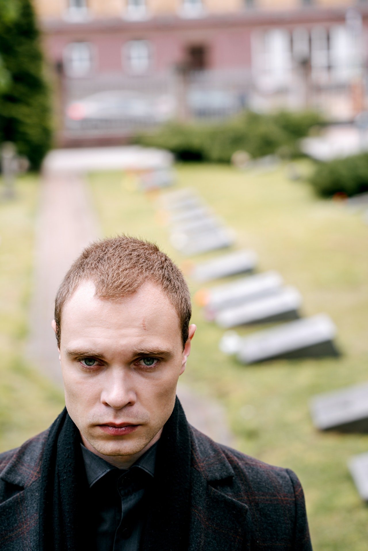 Un hombre con rostro serio y ropa oscura en un cementerio. | Foto: Pexels