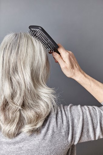 Vue arrière d'une femme brossant de longs cheveux gris. | Photo : Getty Images