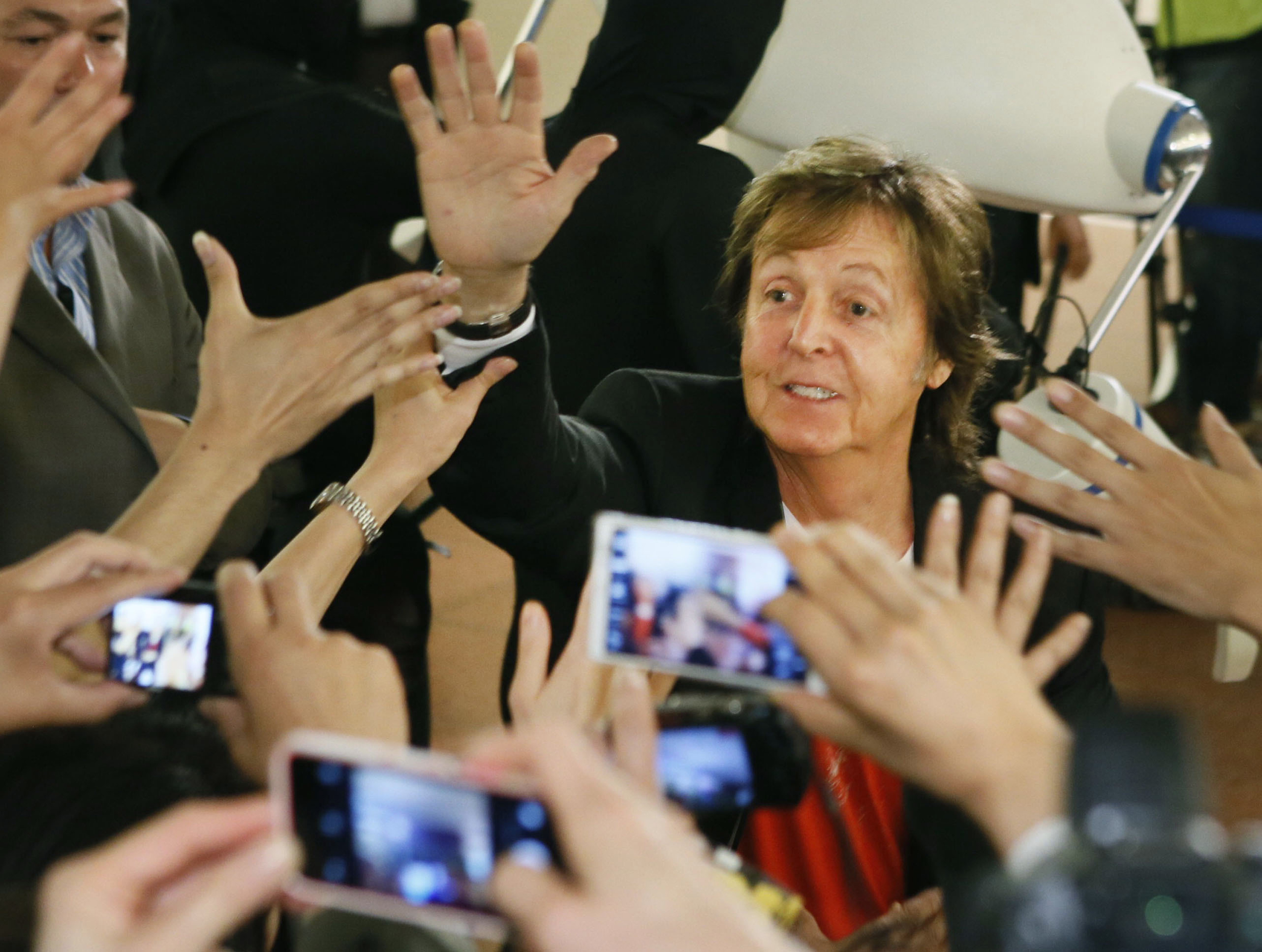 Paul McCartney exchanges high-fives with fans upon arriving at Tokyo's Haneda airport, for concerts in Japan, on May 15, 2014. | Source: Getty Images