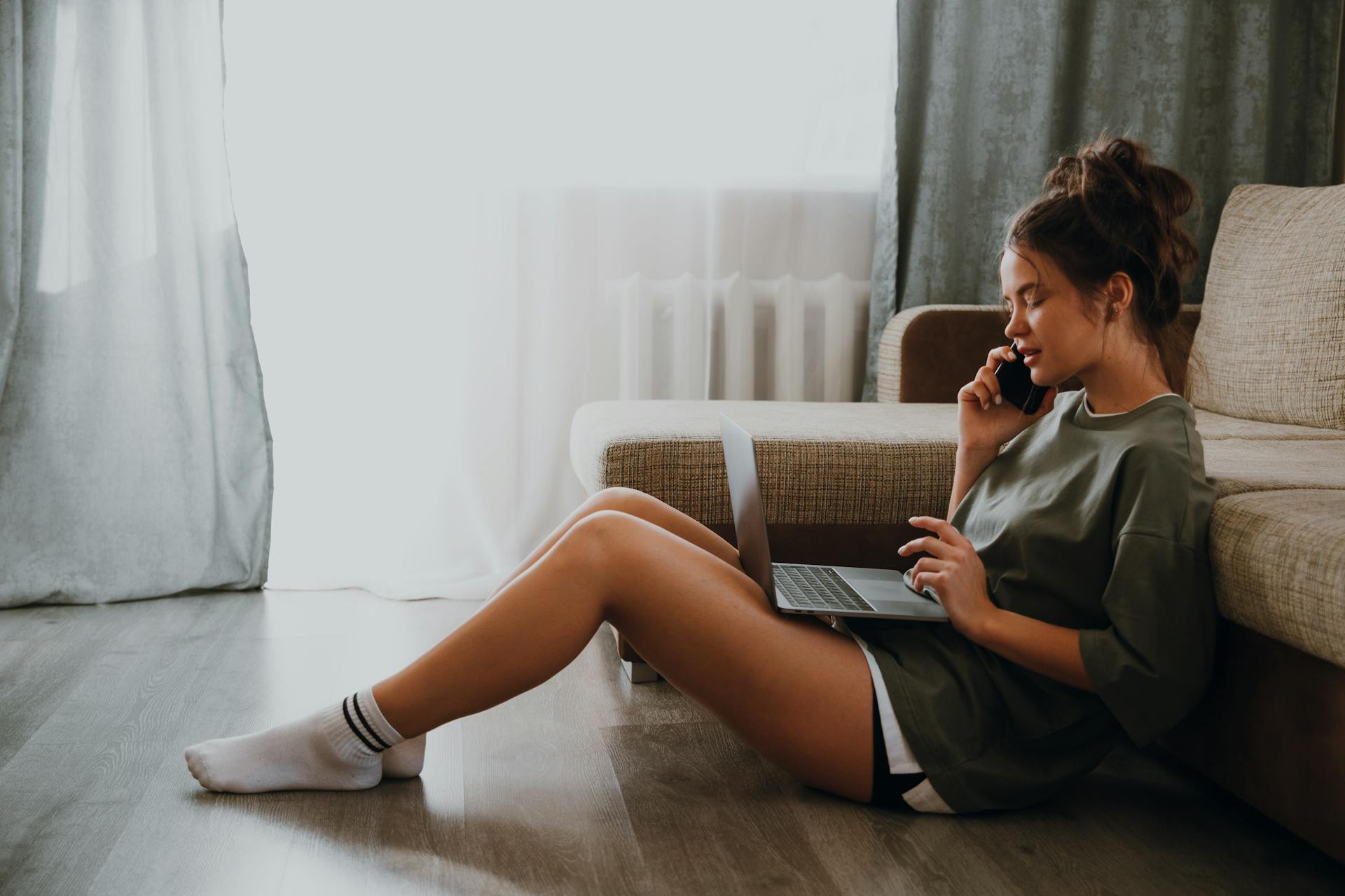 A young woman talking on the phone while using laptop | Source: Pexels