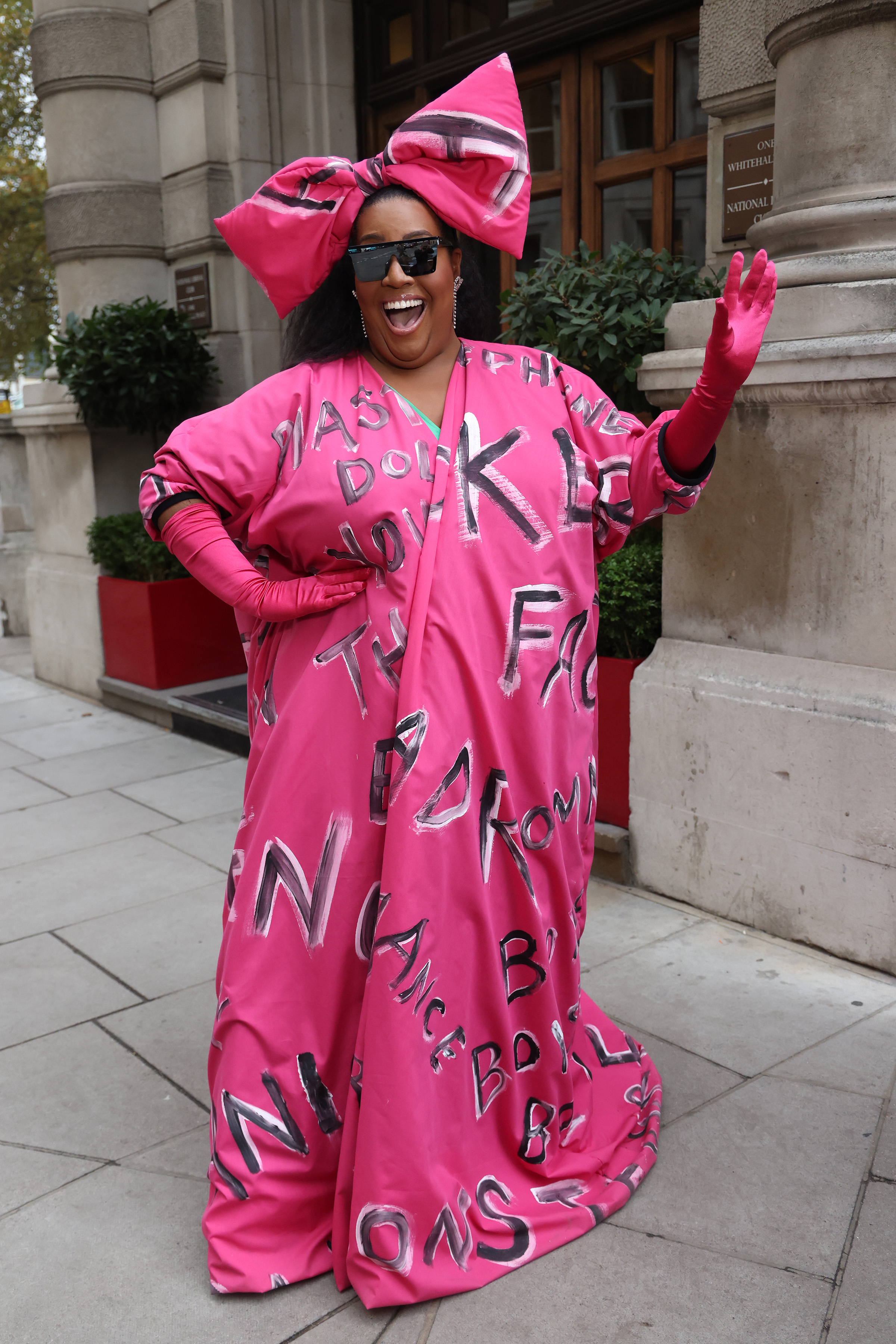 Bubbling with excitement, Hammond waves outside the Corinthia Hotel on 11 November 2021 after filming for "This Morning" and interviewing Lady Gaga. She steals the scene in bright pink, topped with a dramatic oversized bow and gloves, with a gown splashed in bold lettering.
