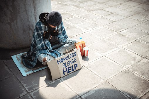 Photo of a young homeless man sitting on the street and begging. | Photo: Getty Images