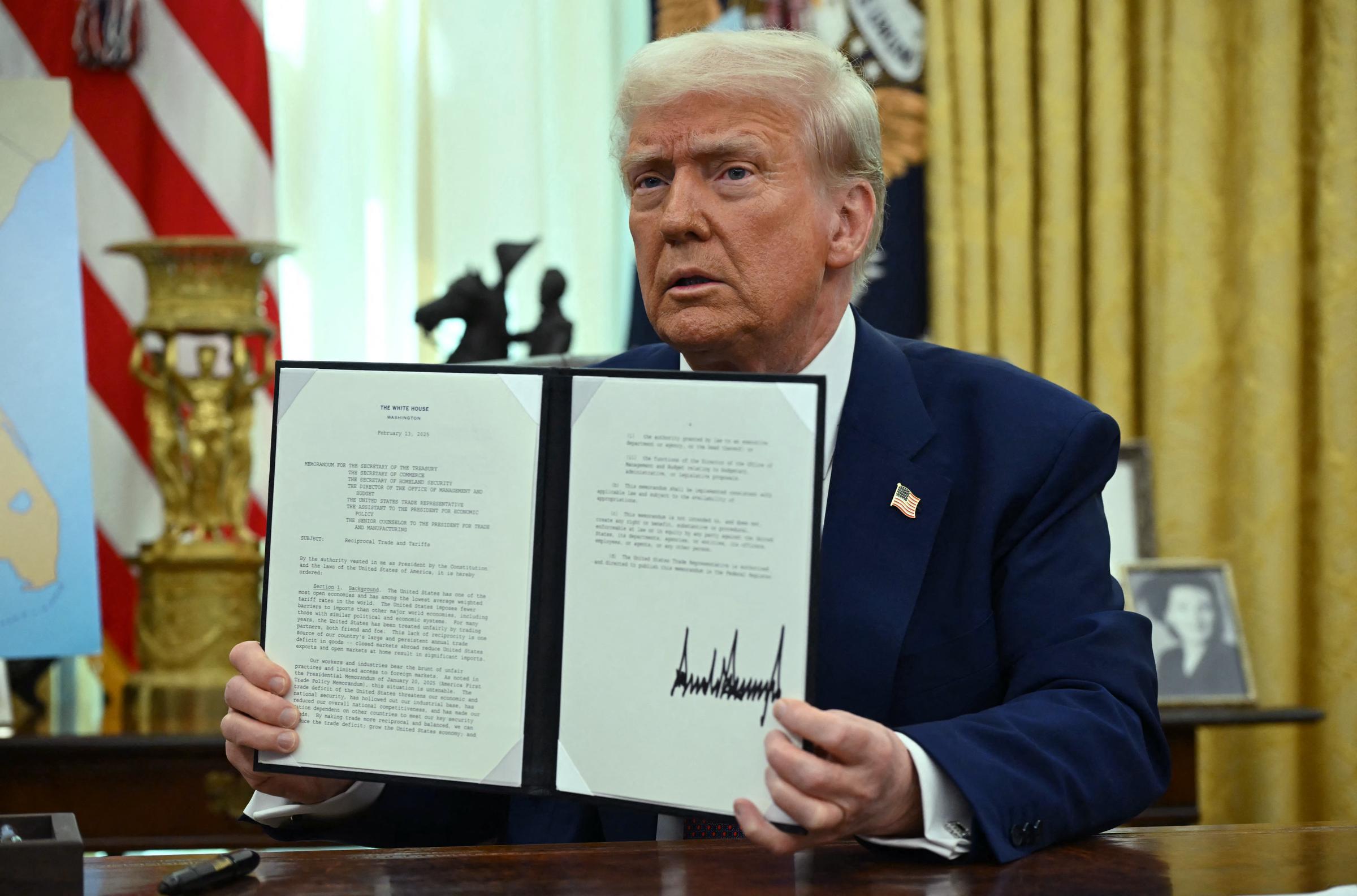 Donald Trump holding up an executive order he signed in the White House in Washington, D.C., on February 13, 2025. | Source: Getty Images