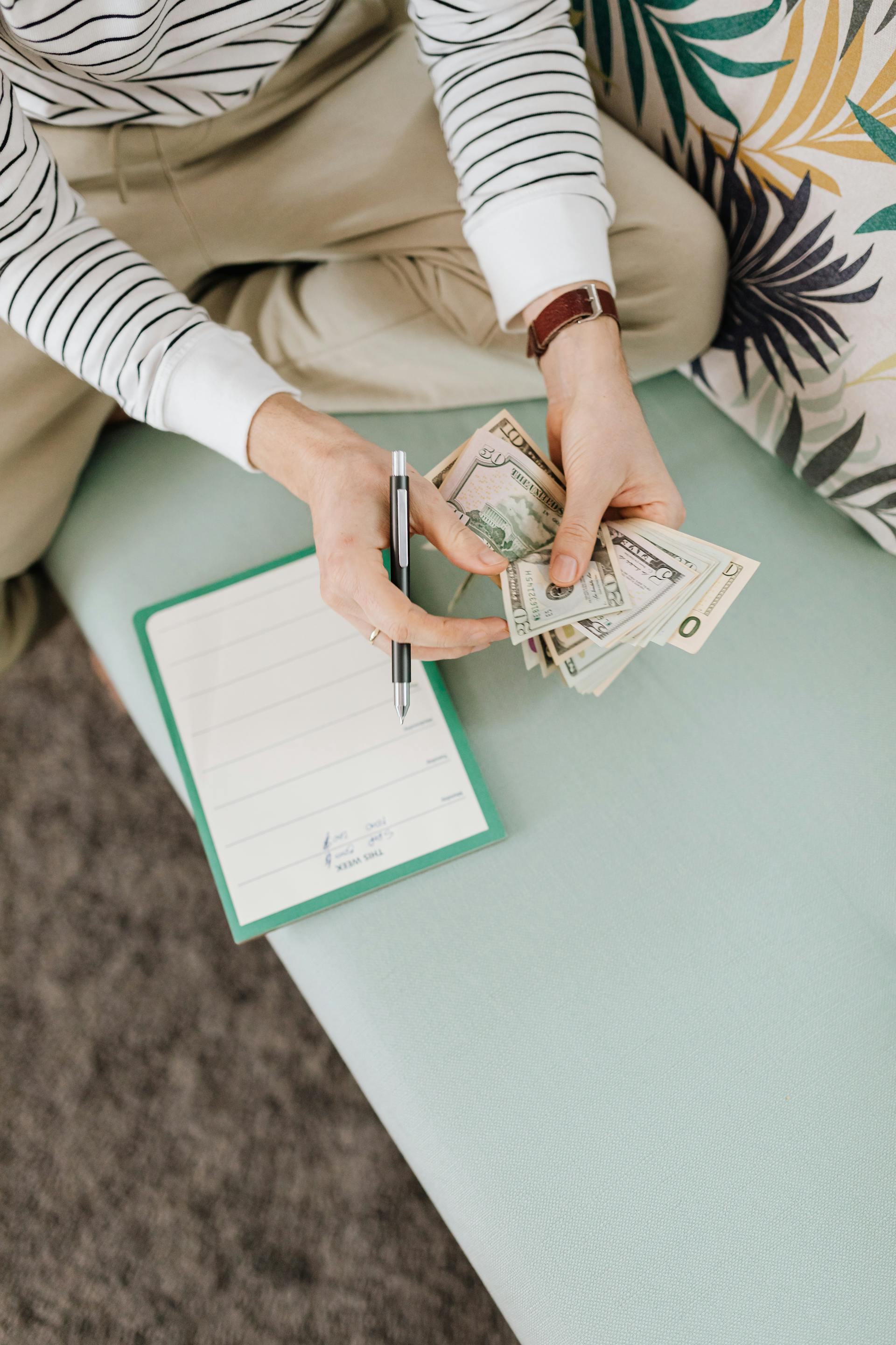 A man counting money while holding a pen | Source: Pexels