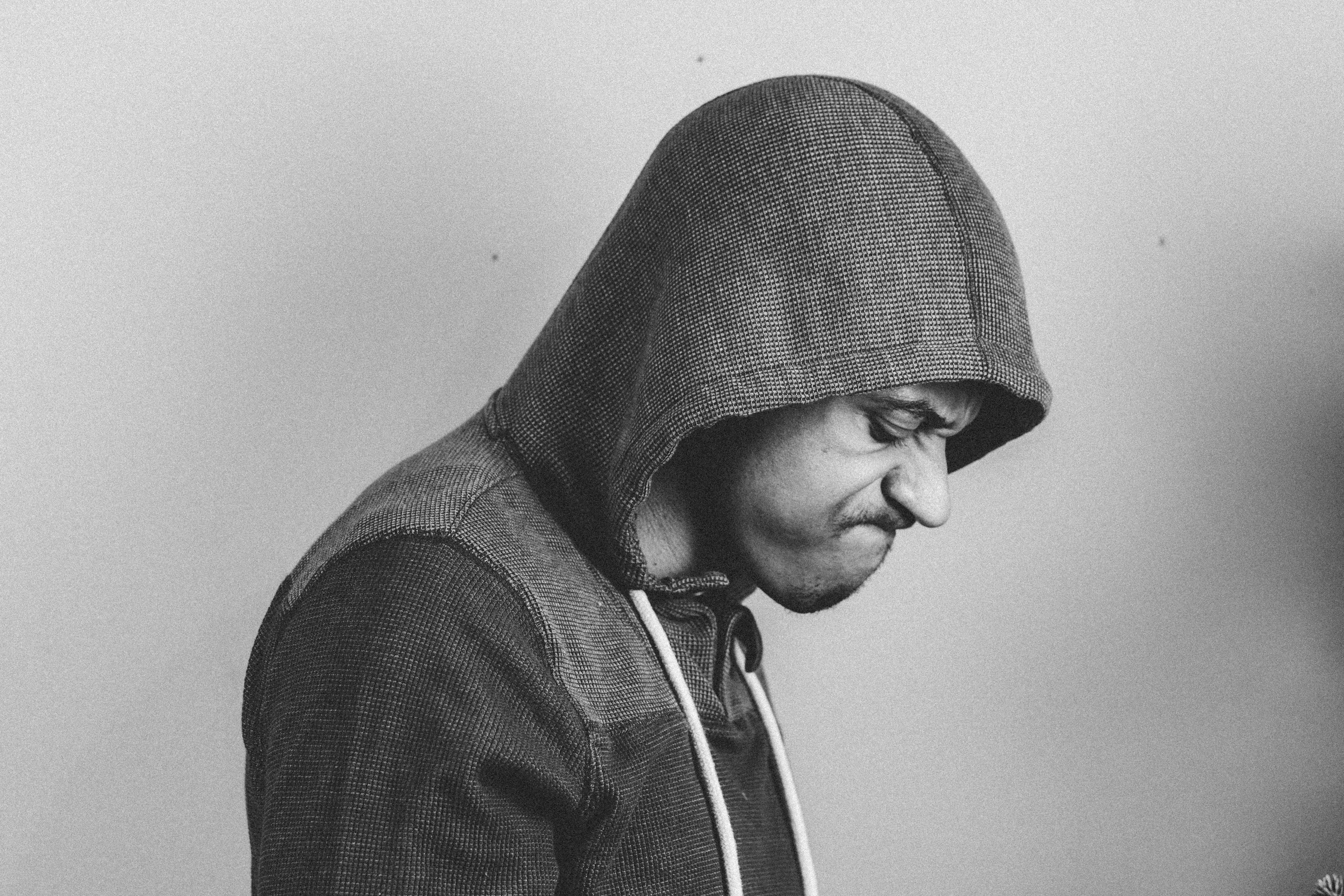 An angry man wearing a hoodie and looking down | Source: Pexels
