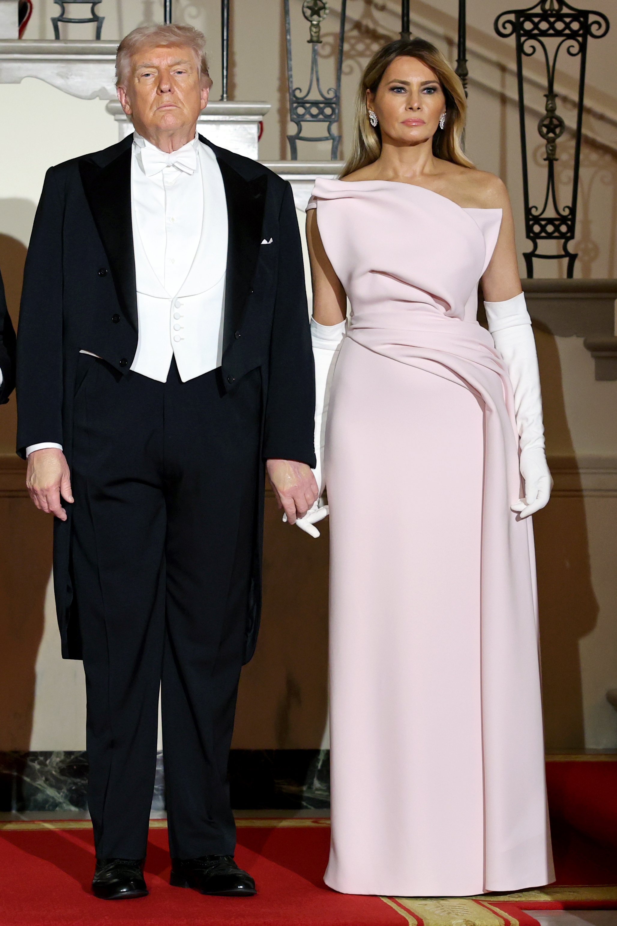 Donald Trump and Melania Trump pose on the Grand Staircase during a State Dinner at the White House, April 28, 2026. | Source: Getty Images