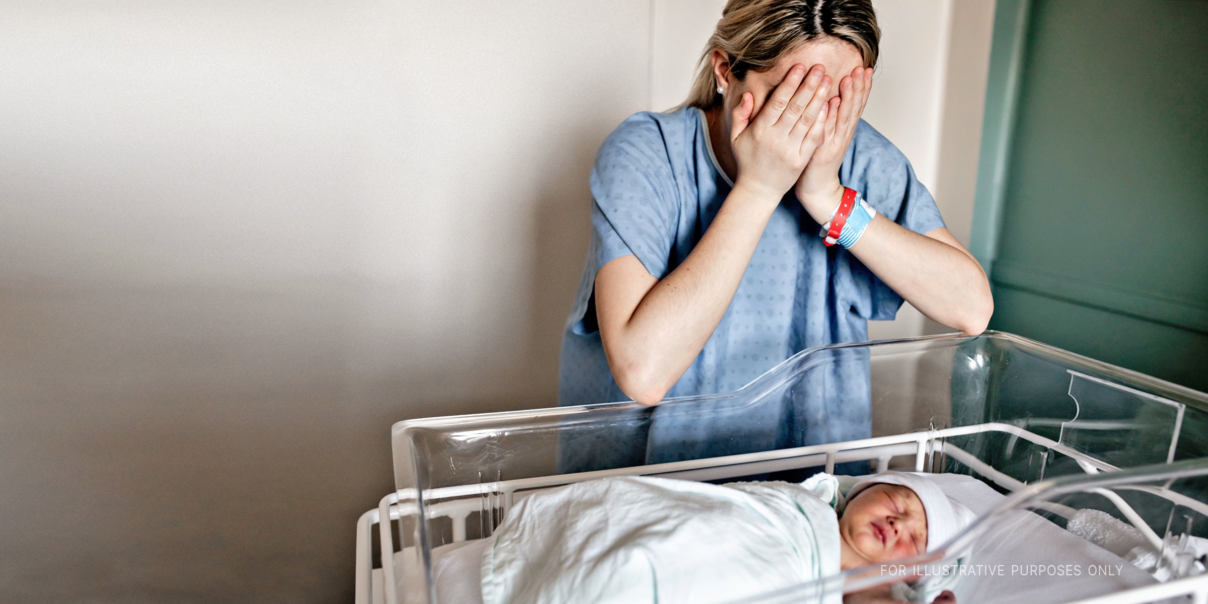 Mother crying near newborn baby in crib | Source: Shutterstock 