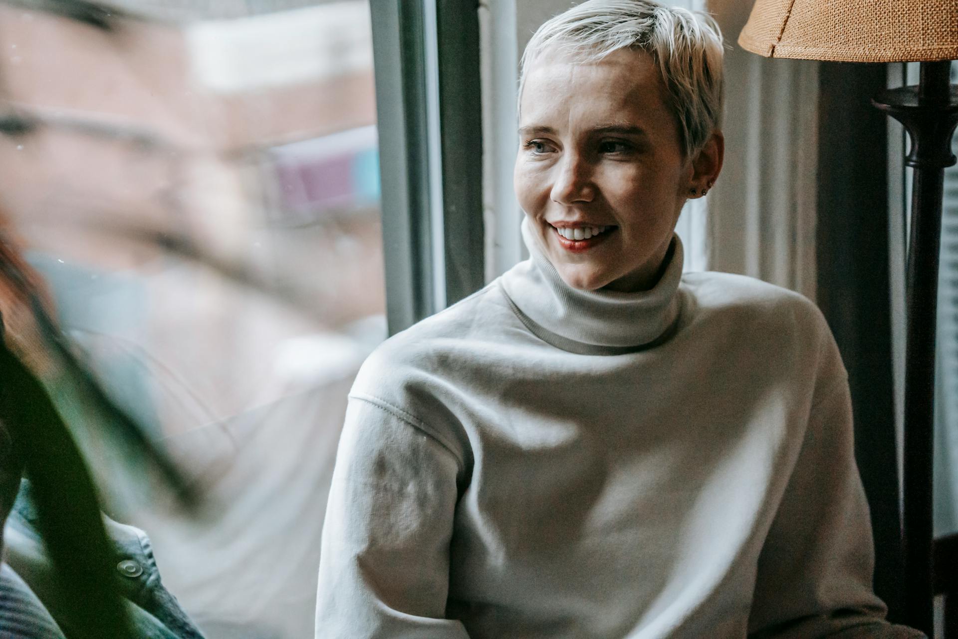 A woman smiling as she looks out a window | Source: Pexels