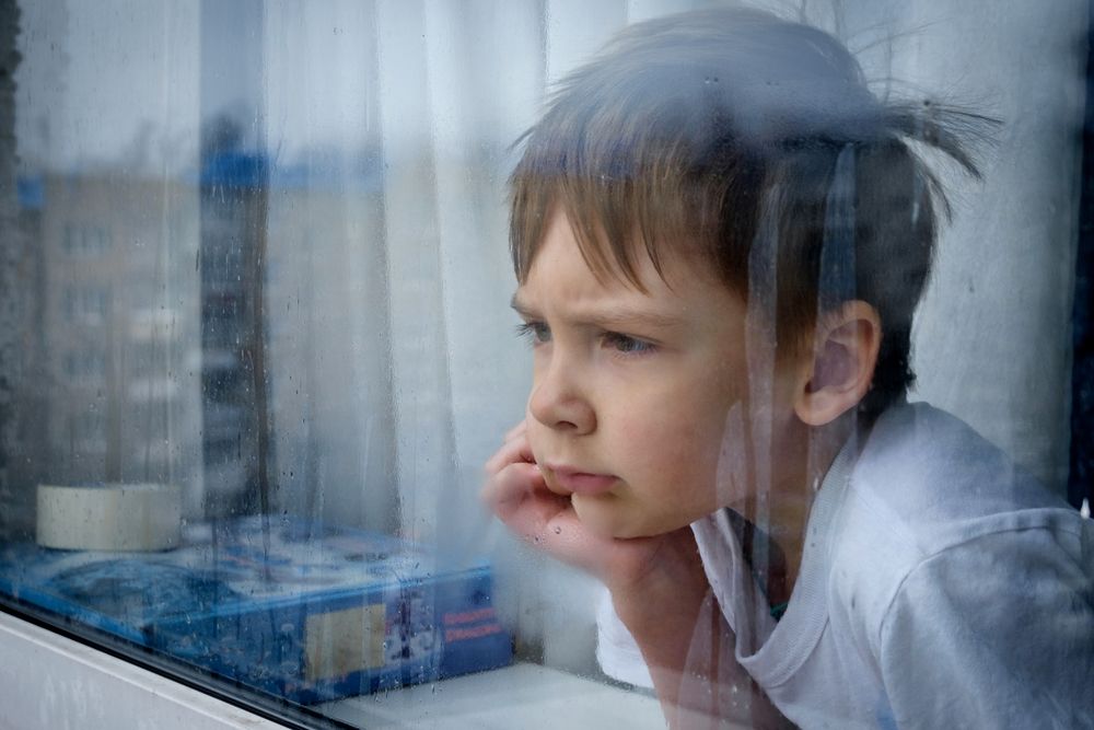 A sad little boy looking out the window. | Source: Shutterstock