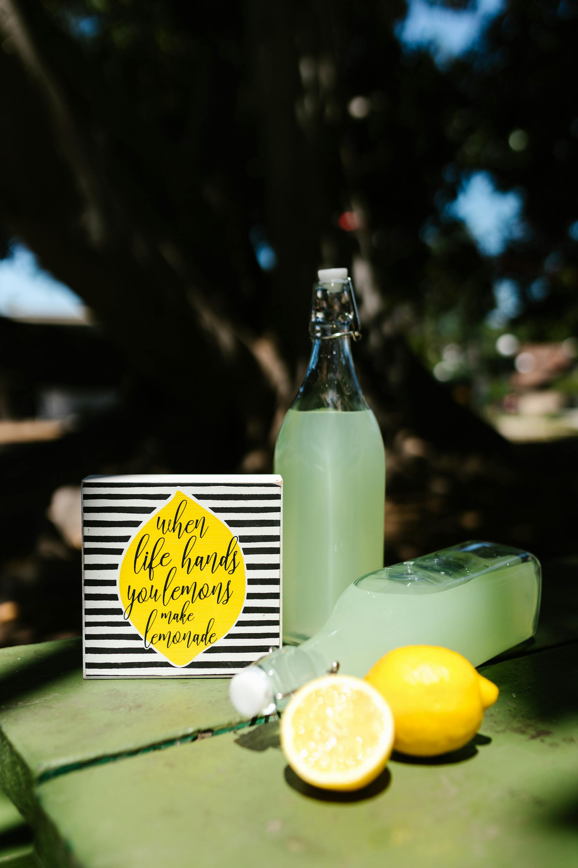 Lemonade glass bottles and lemon slices lying on a table outside | Source: Pexels