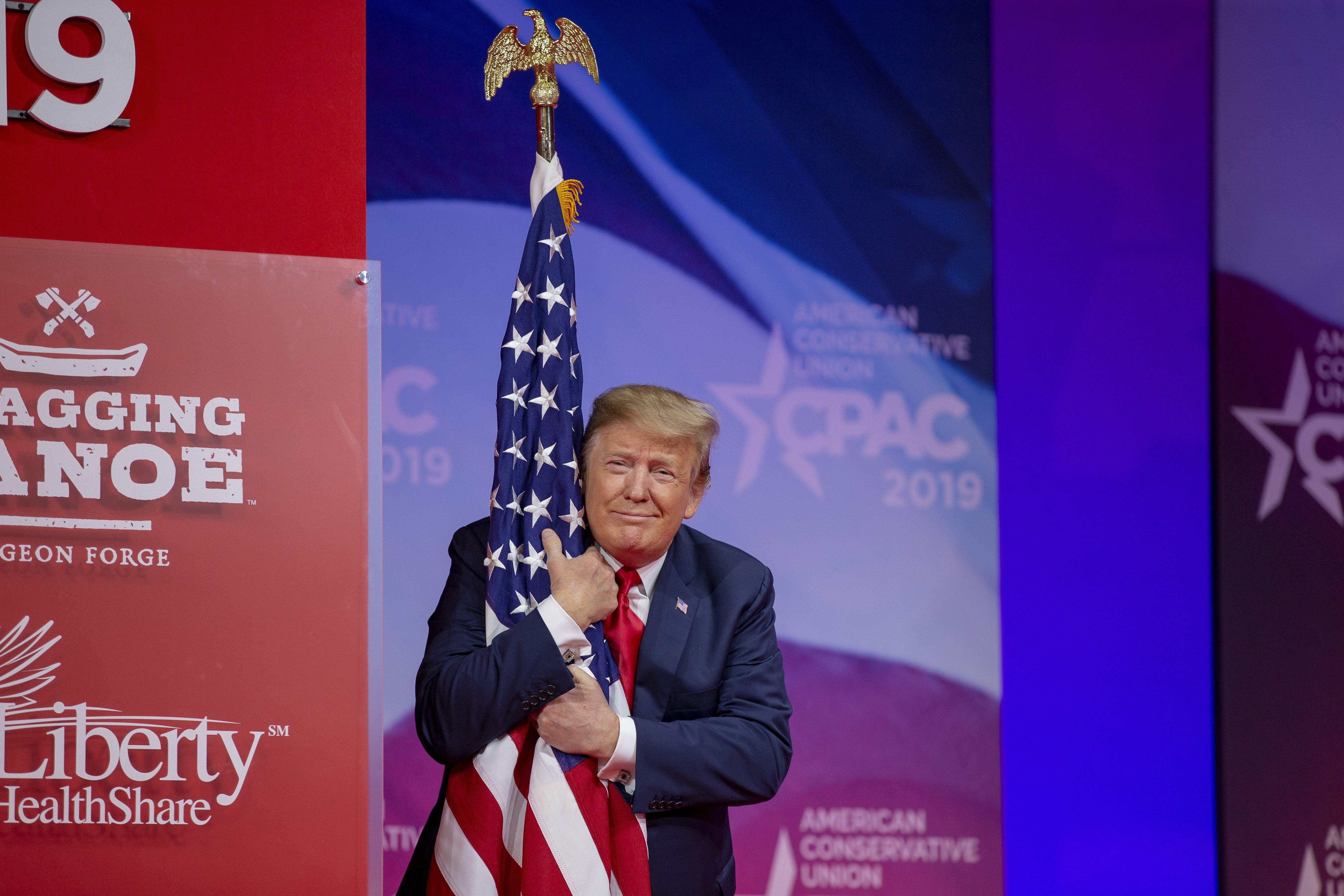 Donald Trump hugging the American flag at the 2019 CPAC in Maryland | Photo: Getty Images