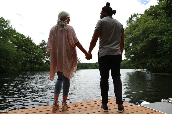 Hombre y mujer tomados de la mano frente a un lago. | Imagen: Getty Images