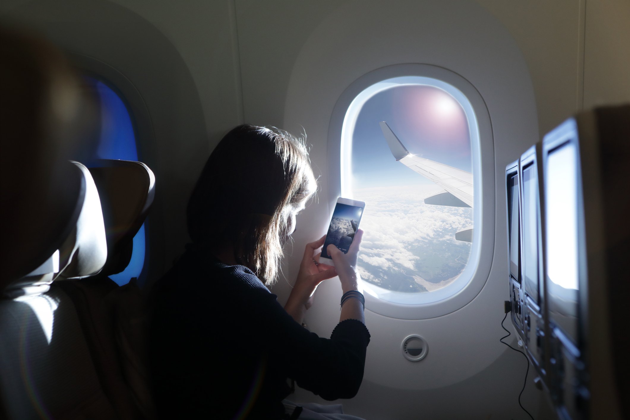 Girl taking photo out of airplane window | Photo: Getty Images