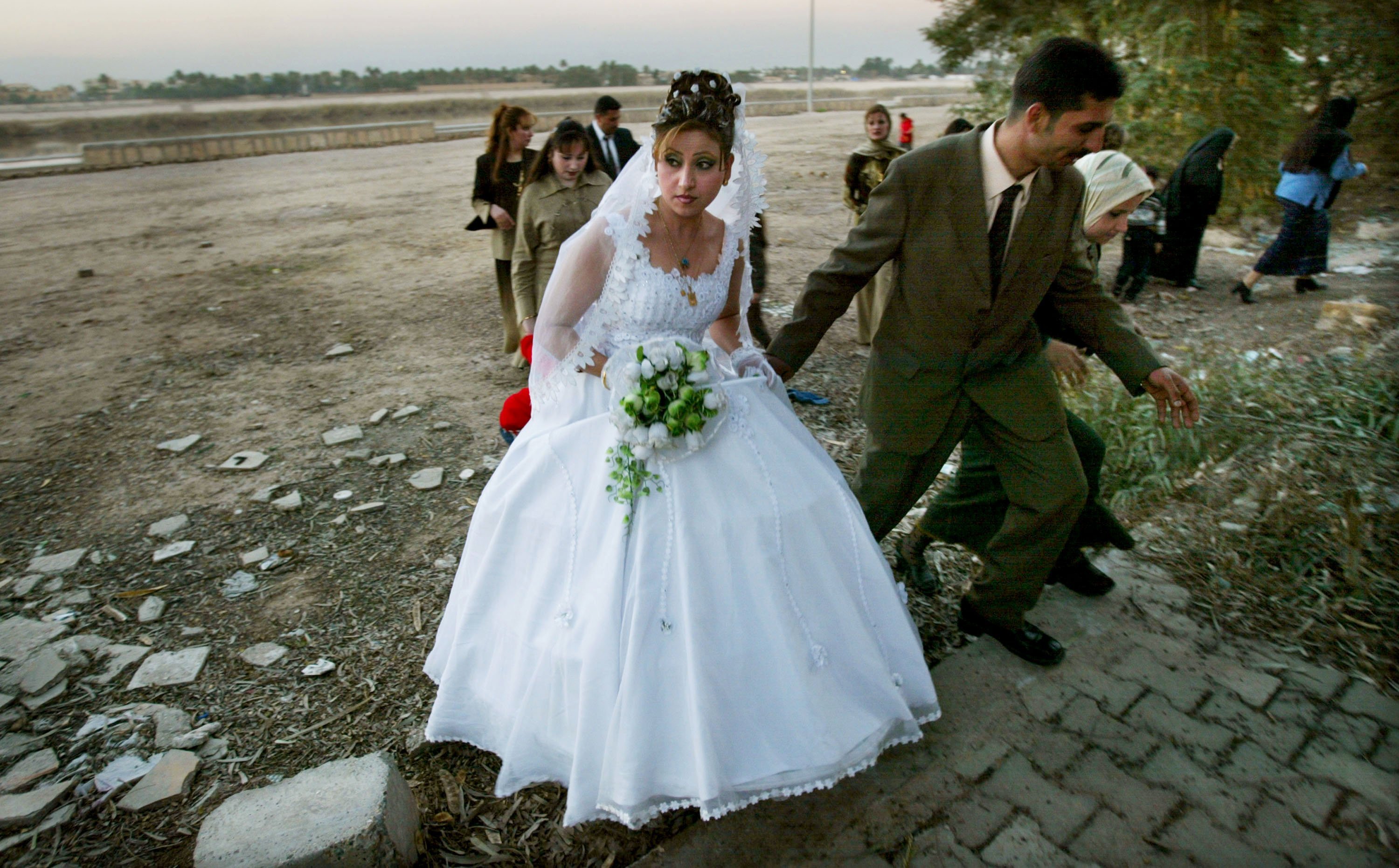 A newly married Iraqi couple walks away from the banks of the Tigris River after posing for photographs February 9, 2004 in Baghdad, Iraq. | Getty Images :photo