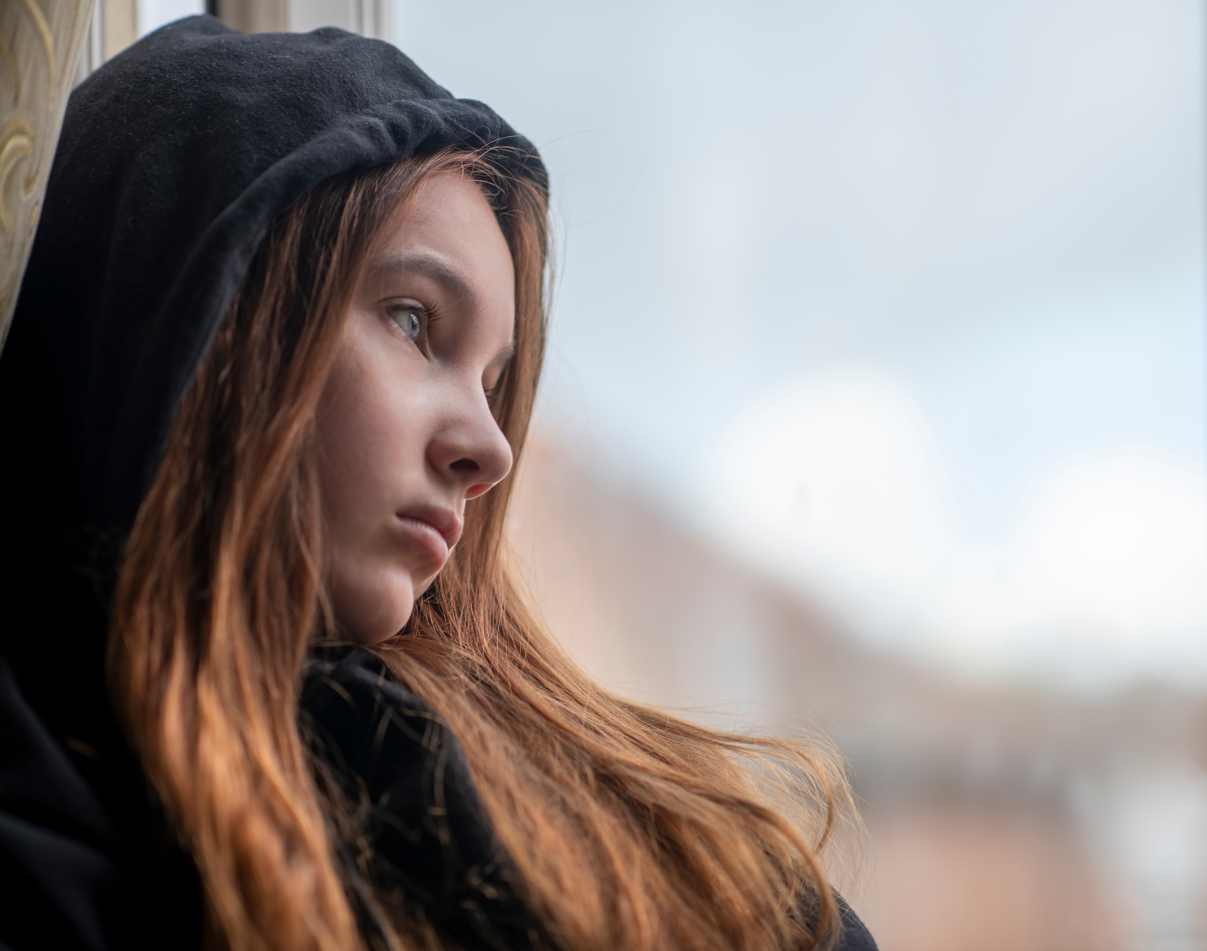 A sad teen girl standing near a window | Source: Shutterstock