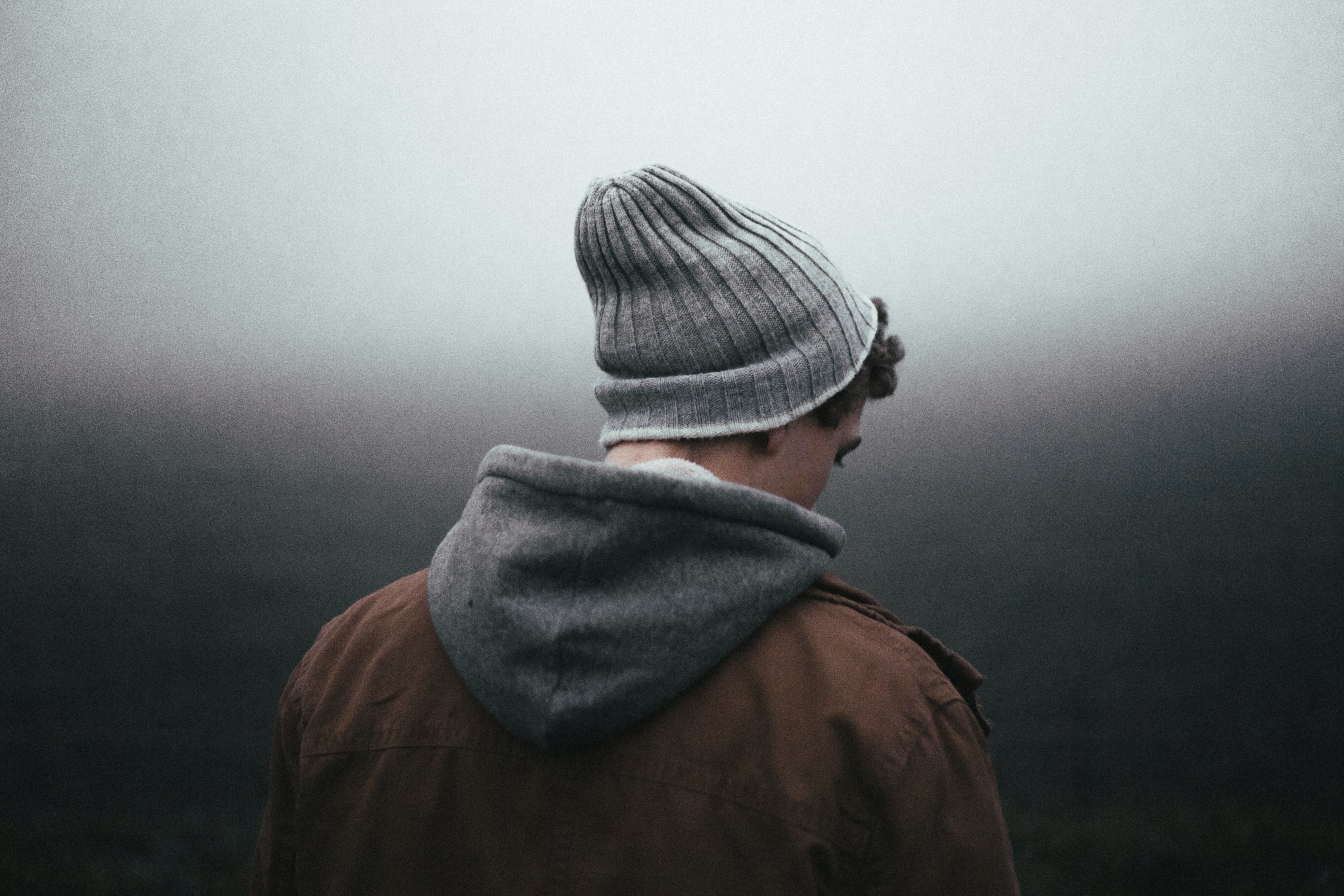 An upset-looking young man looking away from the camera while wearing winter clothes | Source: Unsplash