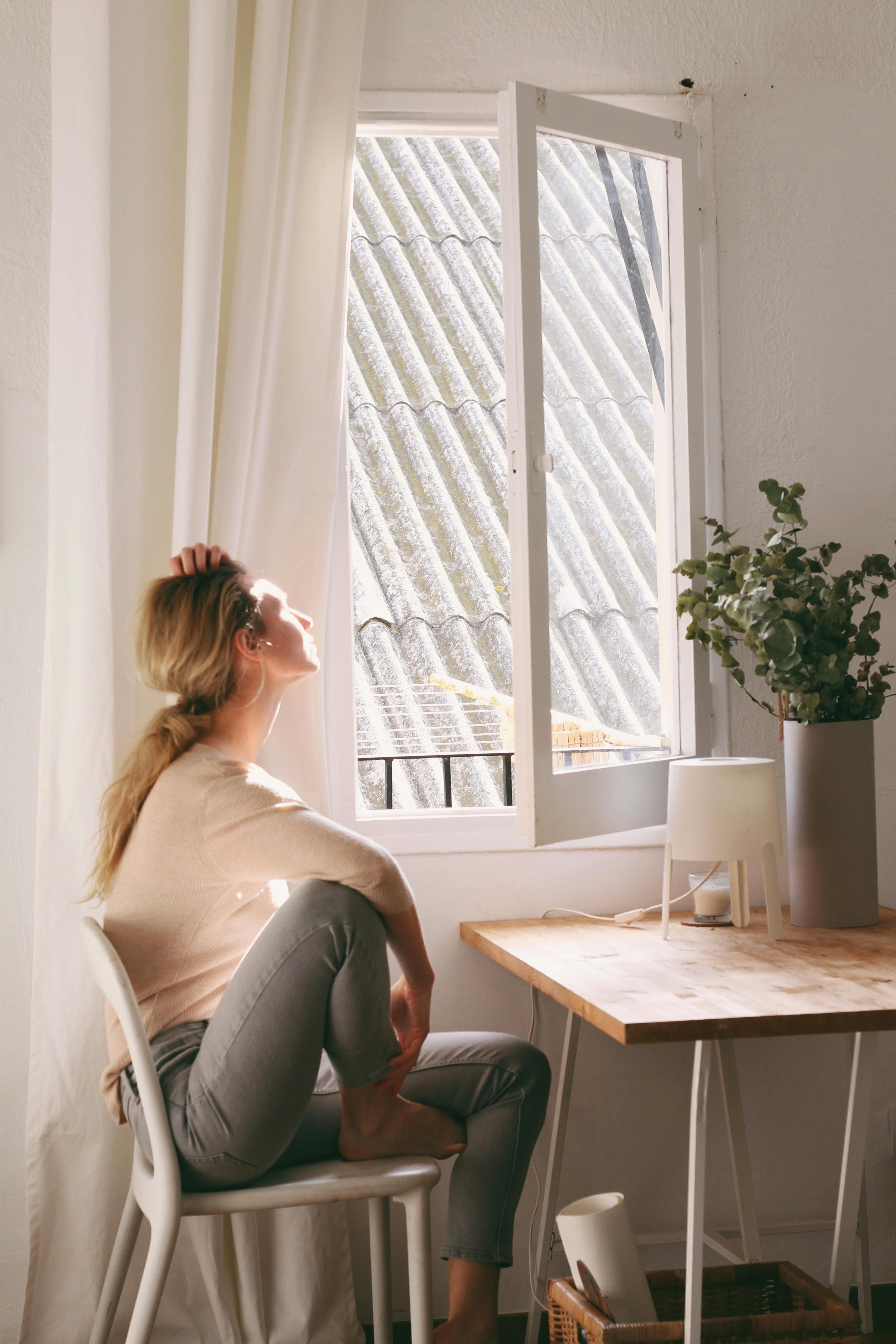 Una mujer joven mirando por la ventana de su apartamento | Fuente: Pexels