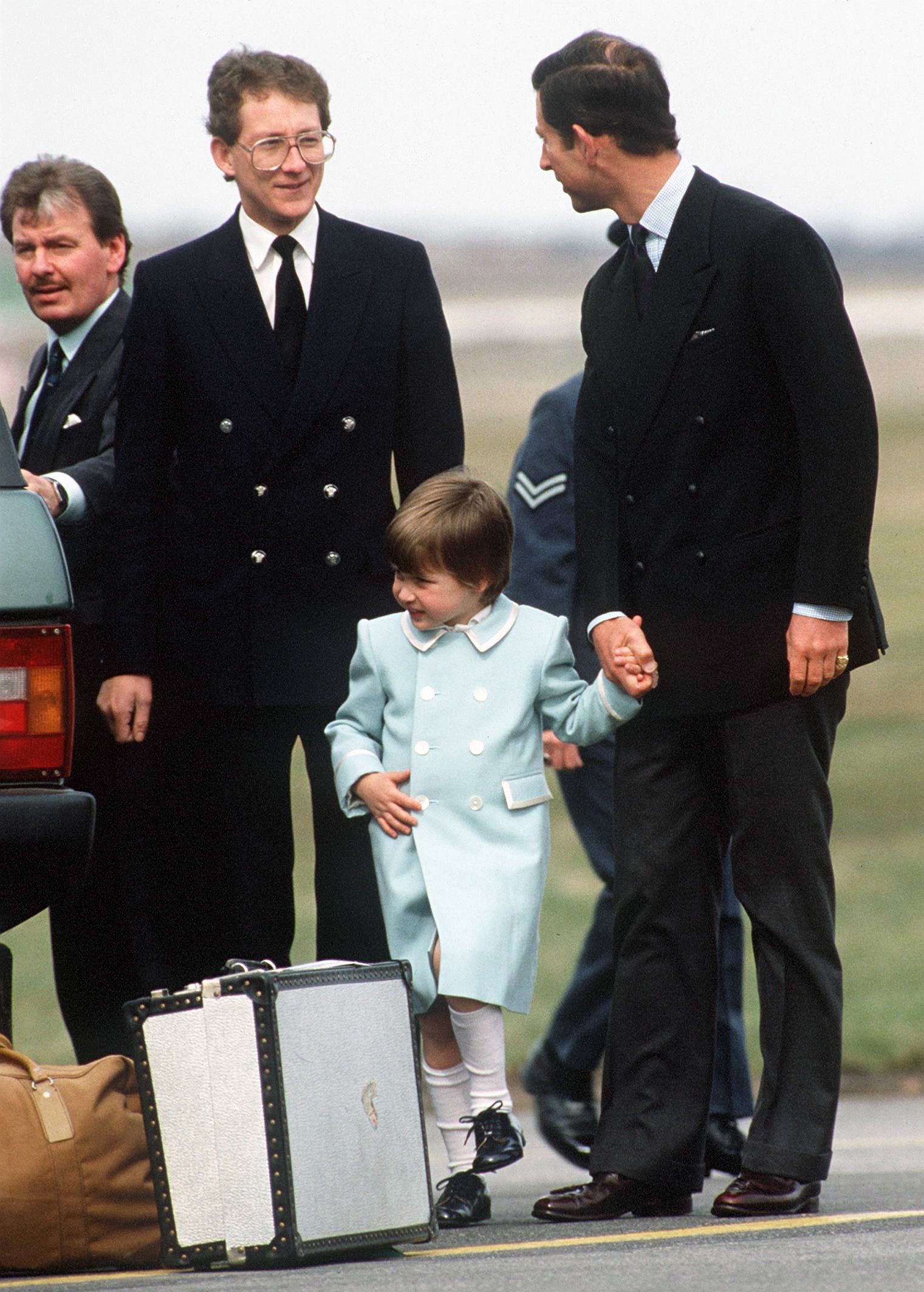 Prinz Charles und Prinz William am Flughafen Aberdeen mit Ken Stronach, dem königlichen Kammerdiener (neben dem Auto, mit Schnurrbart) und dem Chauffeur Tim Williams am 13. April 1987 | Quelle: Getty Images