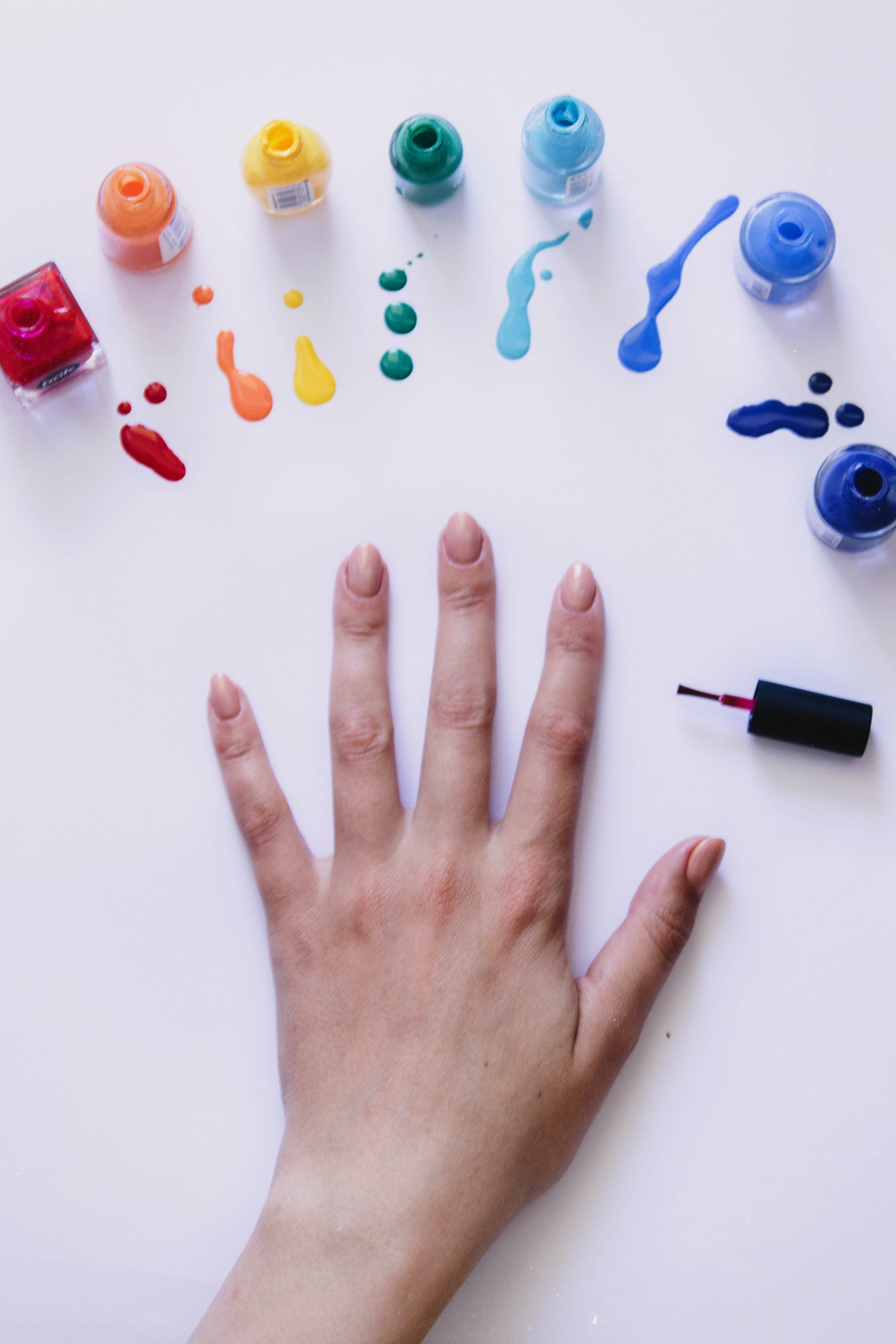 A photo of a woman's hand placed on the table next to nail polishes | Source: Pexels
