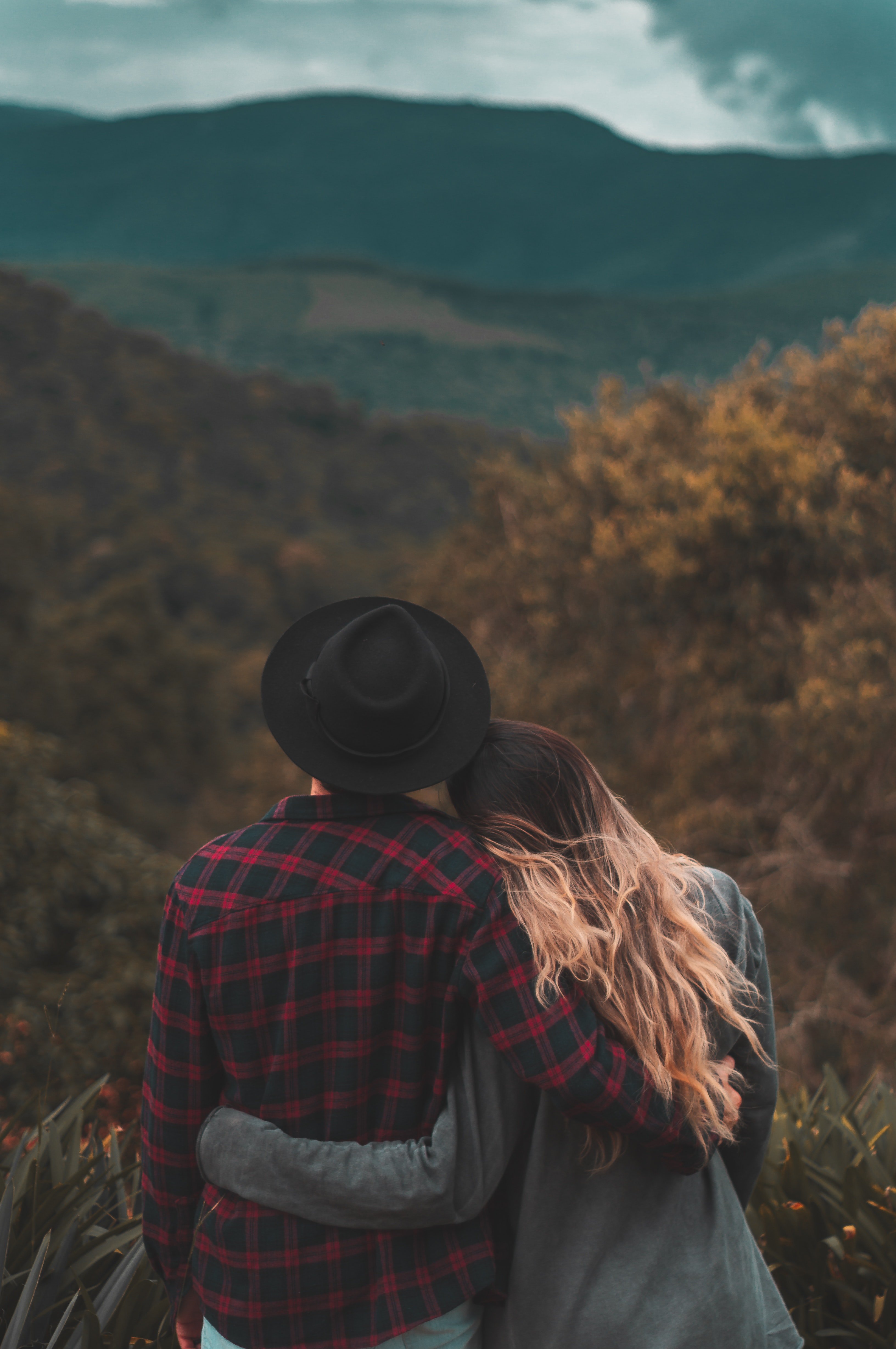A couple standing on top of a hill with the woman resting her head on her man's shoulder | Source: Pexels 