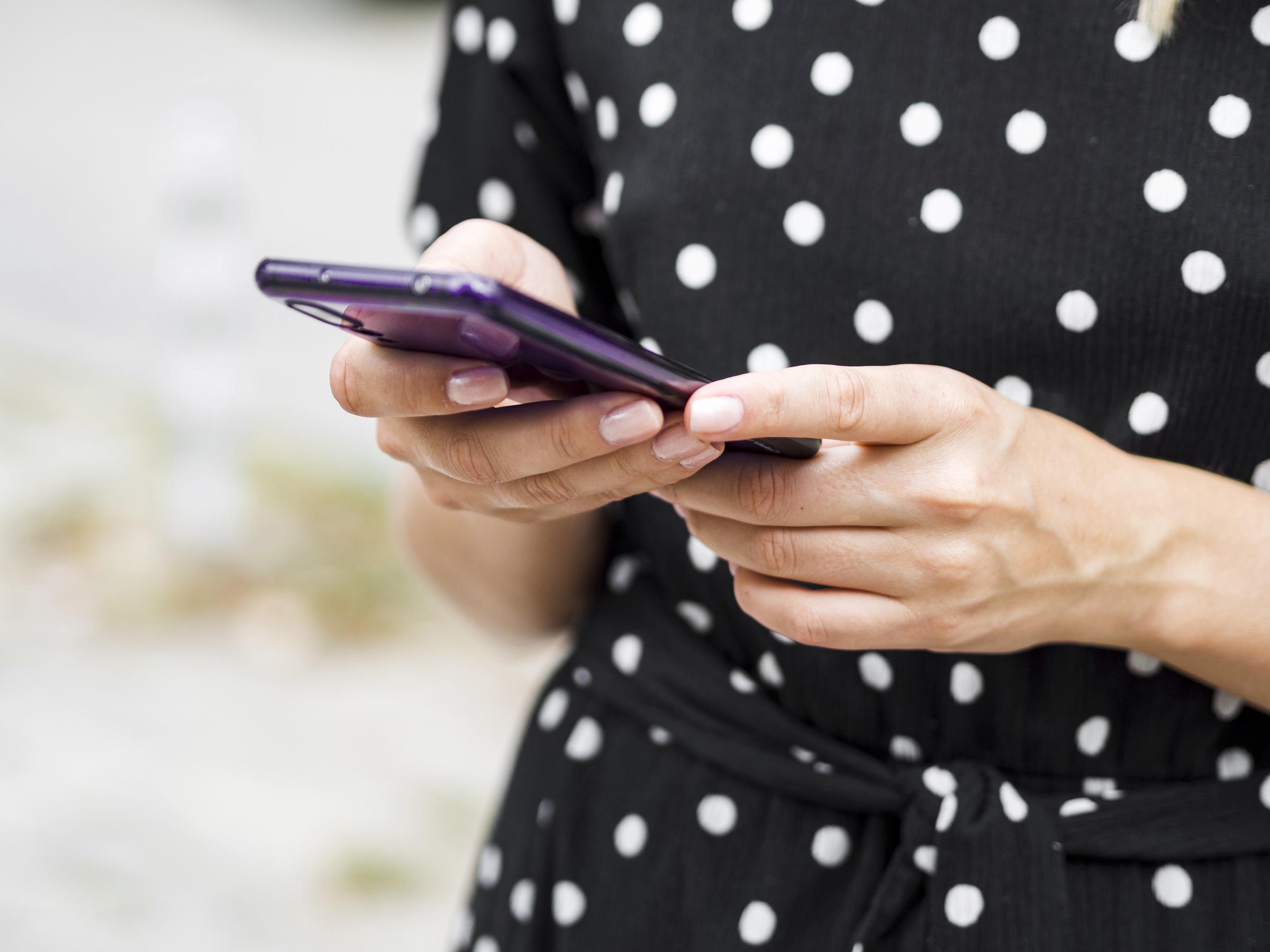 A woman typing a message on her phone | Source: Freepik