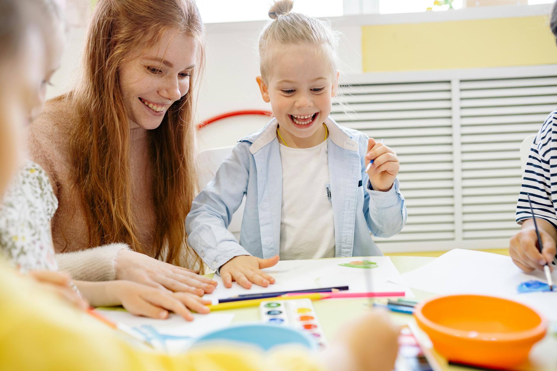 A happy little girl learning how to paint with her teacher | Source: Pexels