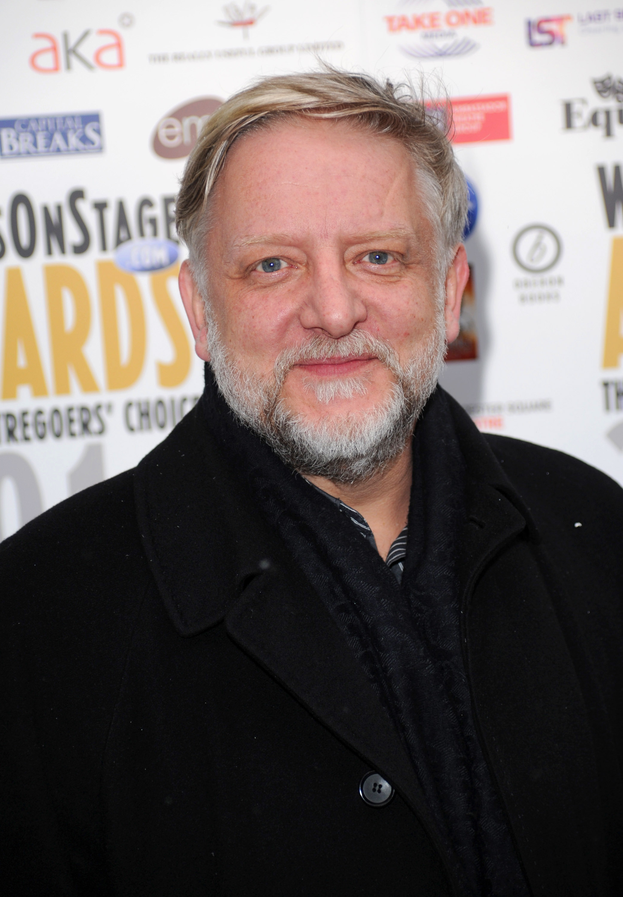 Simon Russell Beale attended the Whatsonstage.com Awards Concert Launch on December 3, 2010, in London, England, wearing a black overcoat and scarf. With his signature silver beard and friendly demeanor, he posed warmly for photos at the theater-focused fan-voted event.